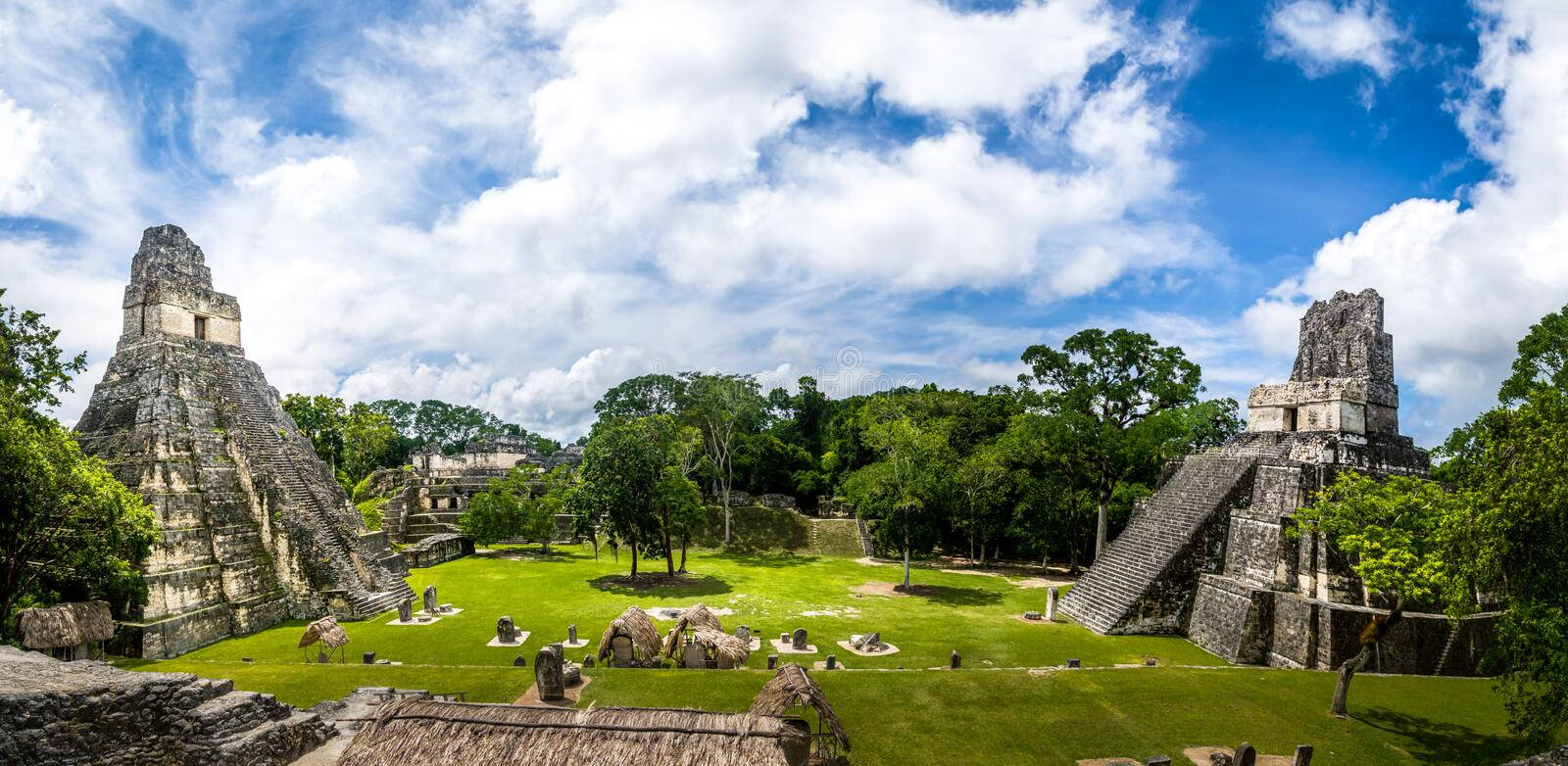 Guatemala 桌布 壁紙 — 古老的馬雅金字塔從充滿活力的綠草中升起，在點綴著蓬鬆白雲的明亮藍天下。