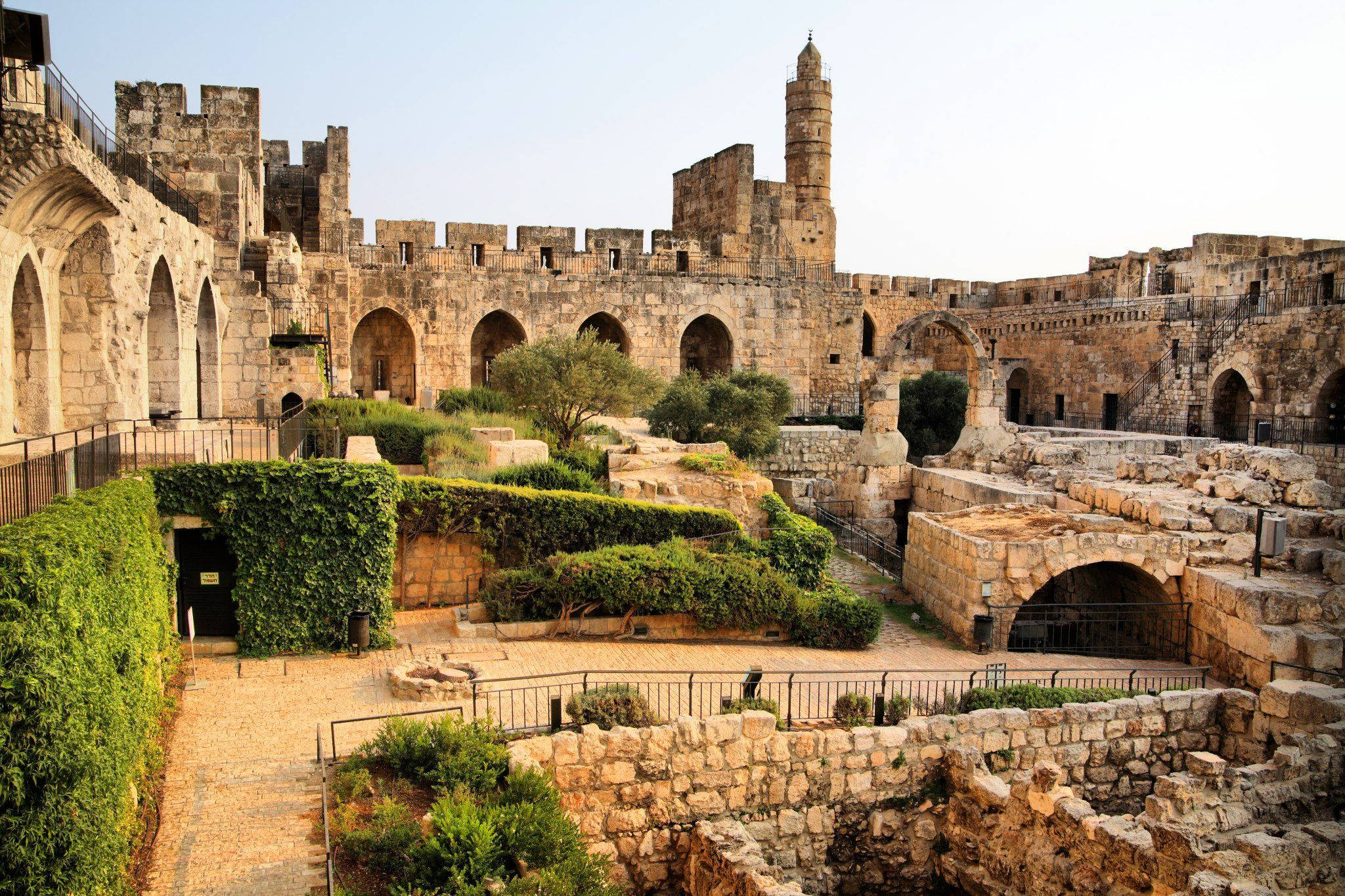 Israel 桌布 壁紙 — 古老石城堡，擁有拱形步道和塔樓，在明亮的日光下被茂密的綠植環繞。