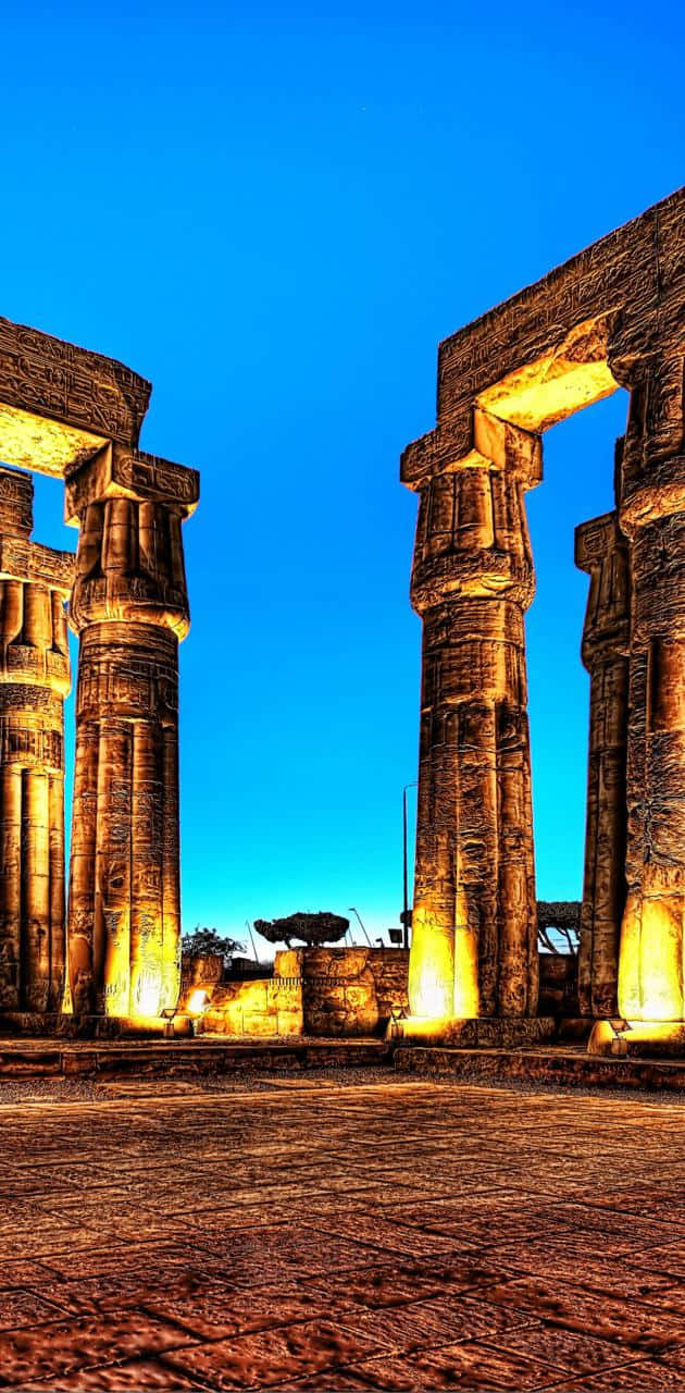 egyptian 桌布 壁紙 — 古老石廟柱在深藍漸變的暮色天空下溫暖地發光。