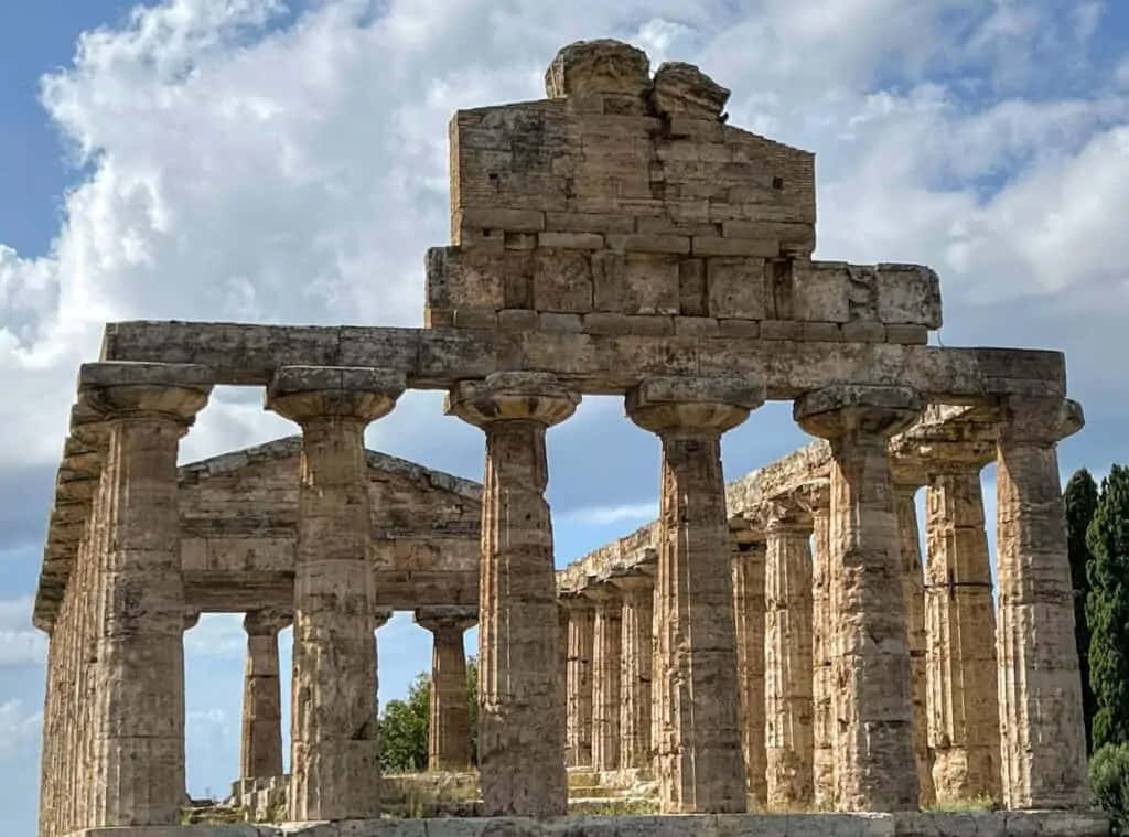 Attraction 桌布 壁紙 — 古老石廟遺跡，高聳的柱子矗立在明亮的藍天下，飄著 fluffy 的白雲。