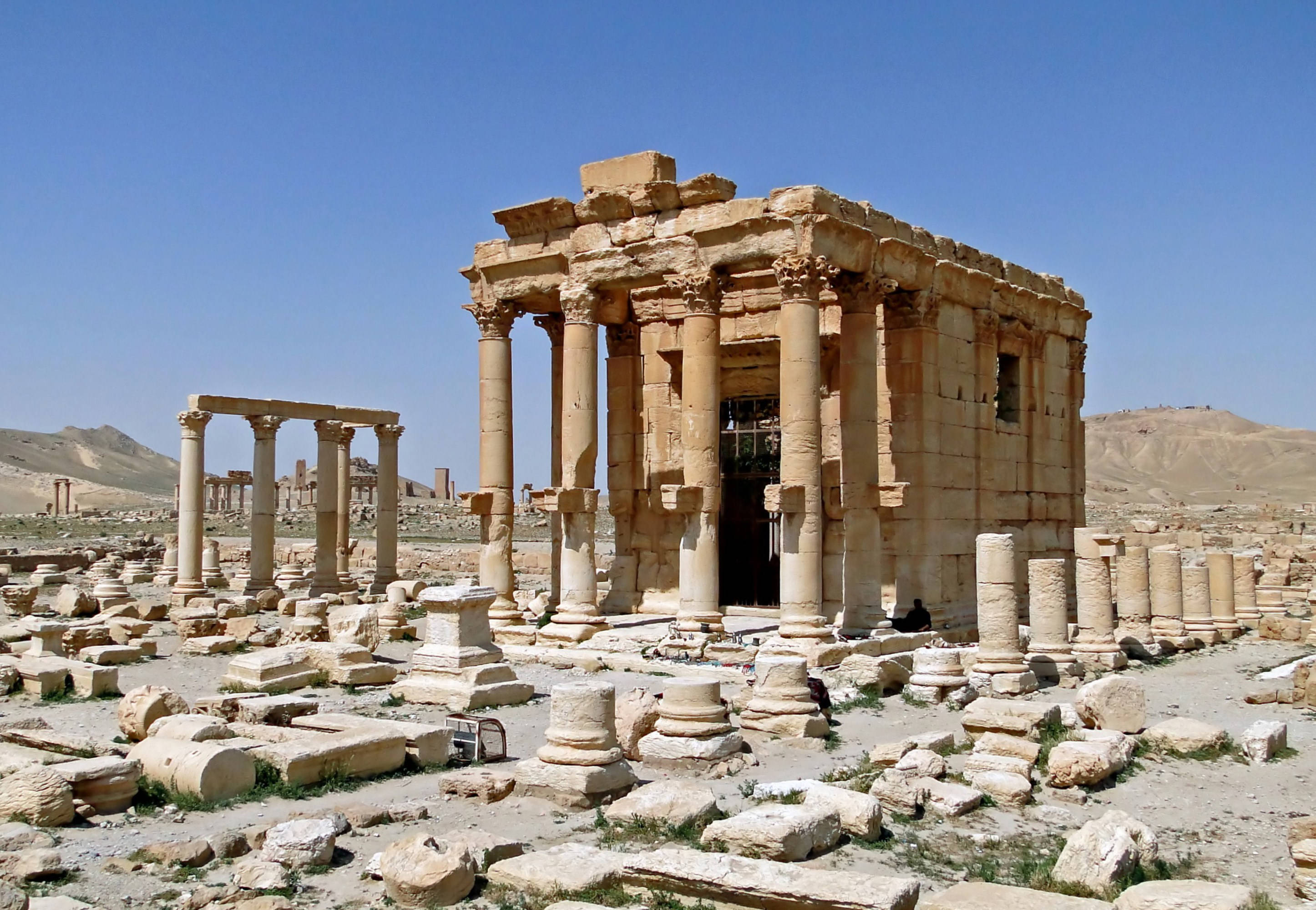 Syria 桌布 壁紙 — 古老石廟遺跡中，高聳的柱子矗立在散落的瓦礫之間，在沙漠景觀中，天空清澈湛藍。