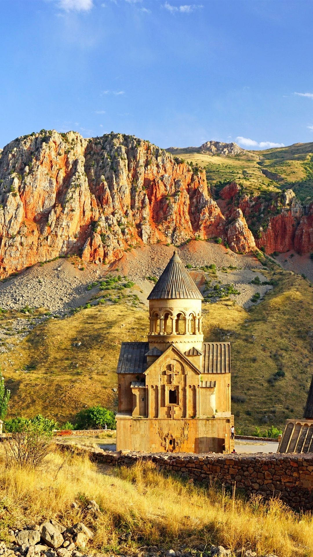 Armenia 桌布 壁紙 — 古老石教堂，錐形屋頂，在清澈藍天下，孤獨地聳立於高聳的橙紅色懸崖前。