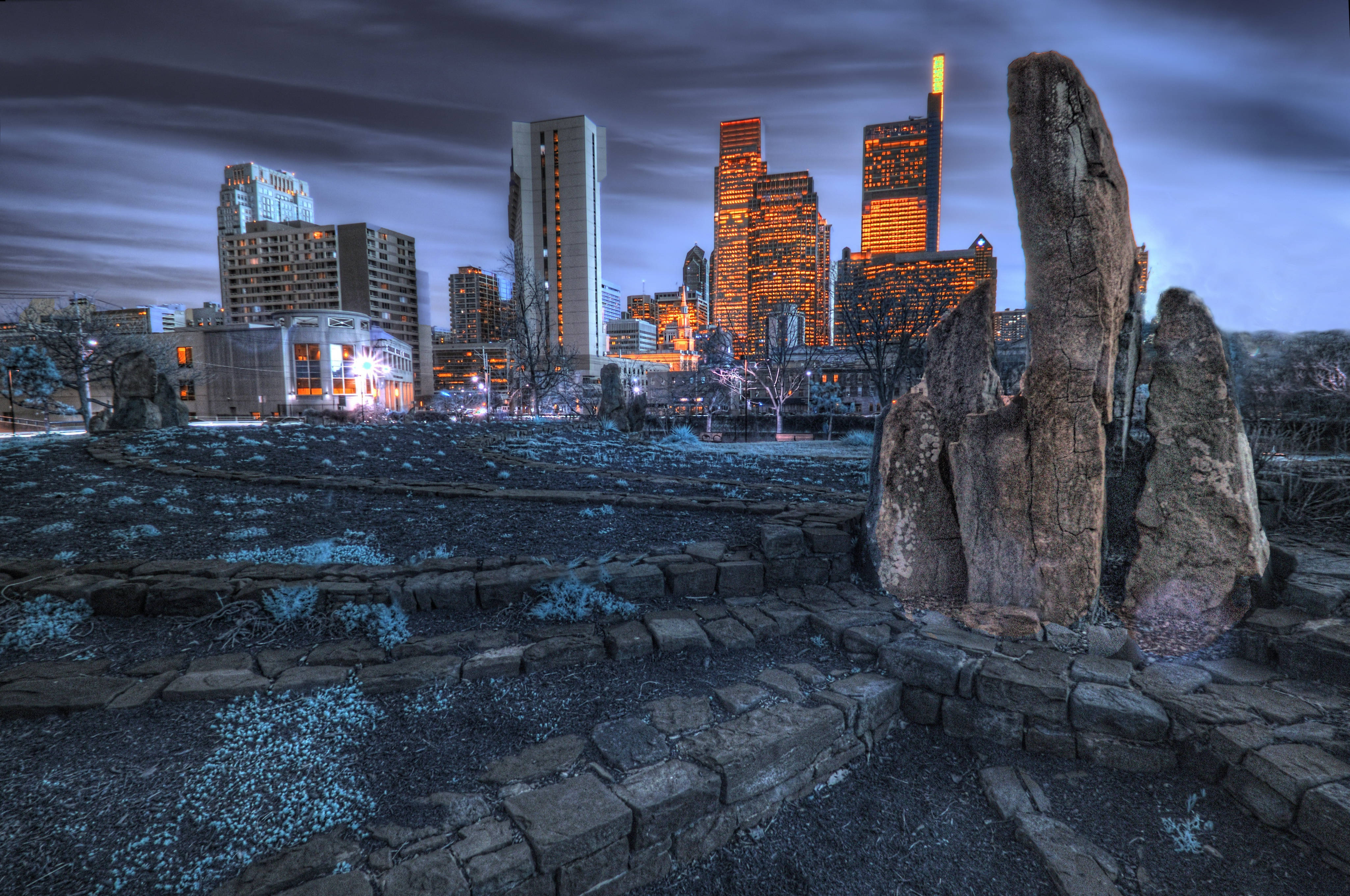 Philadelphia 桌布 壁紙 — 古老石柱矗立在前景，背景是暮色中發光的城市天際線和條紋雲。