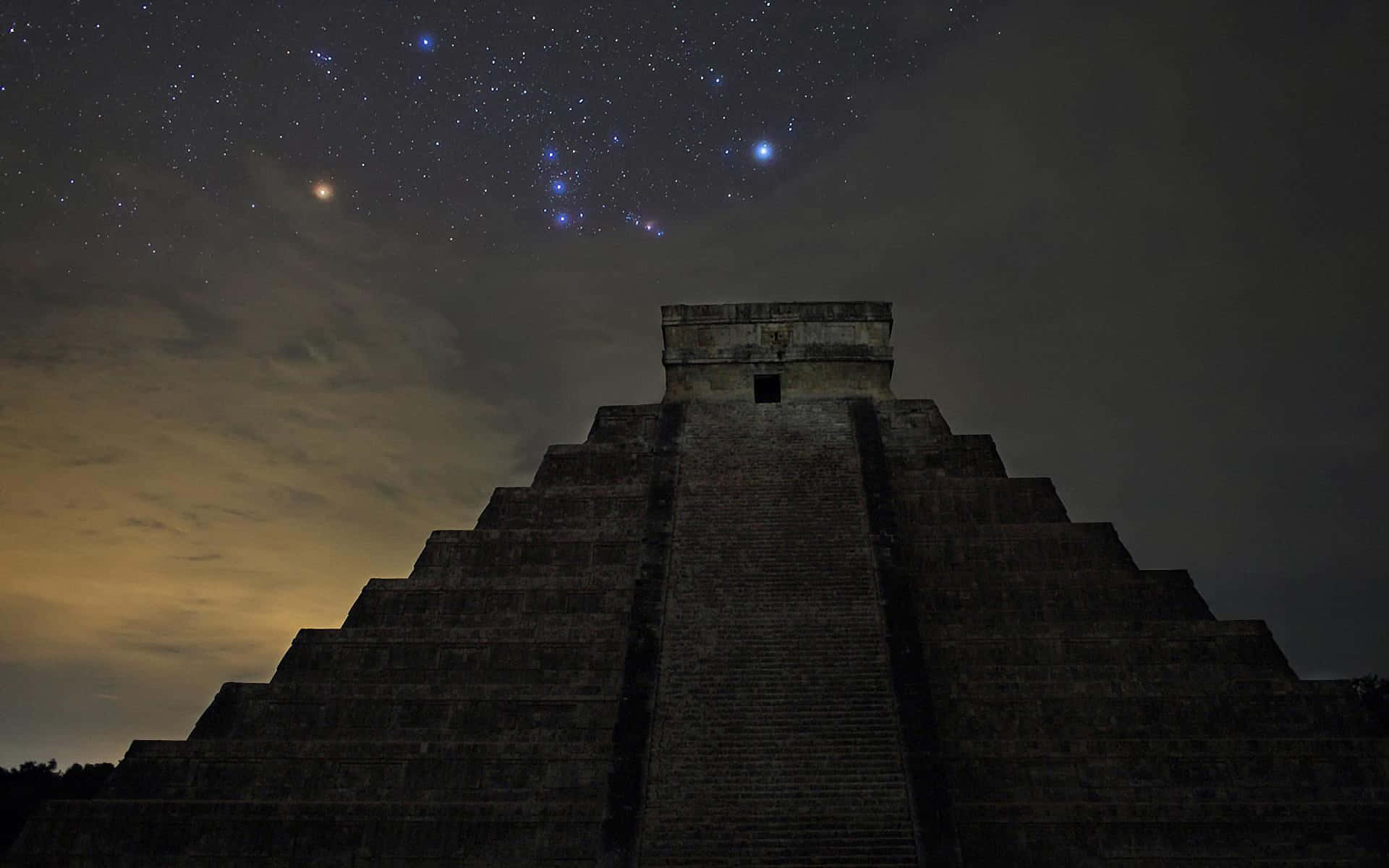 pyramid 桌布 壁紙 — 古老石金字塔在繁星點點的夜空下呈現剪影，可見星座和發光的地平線。