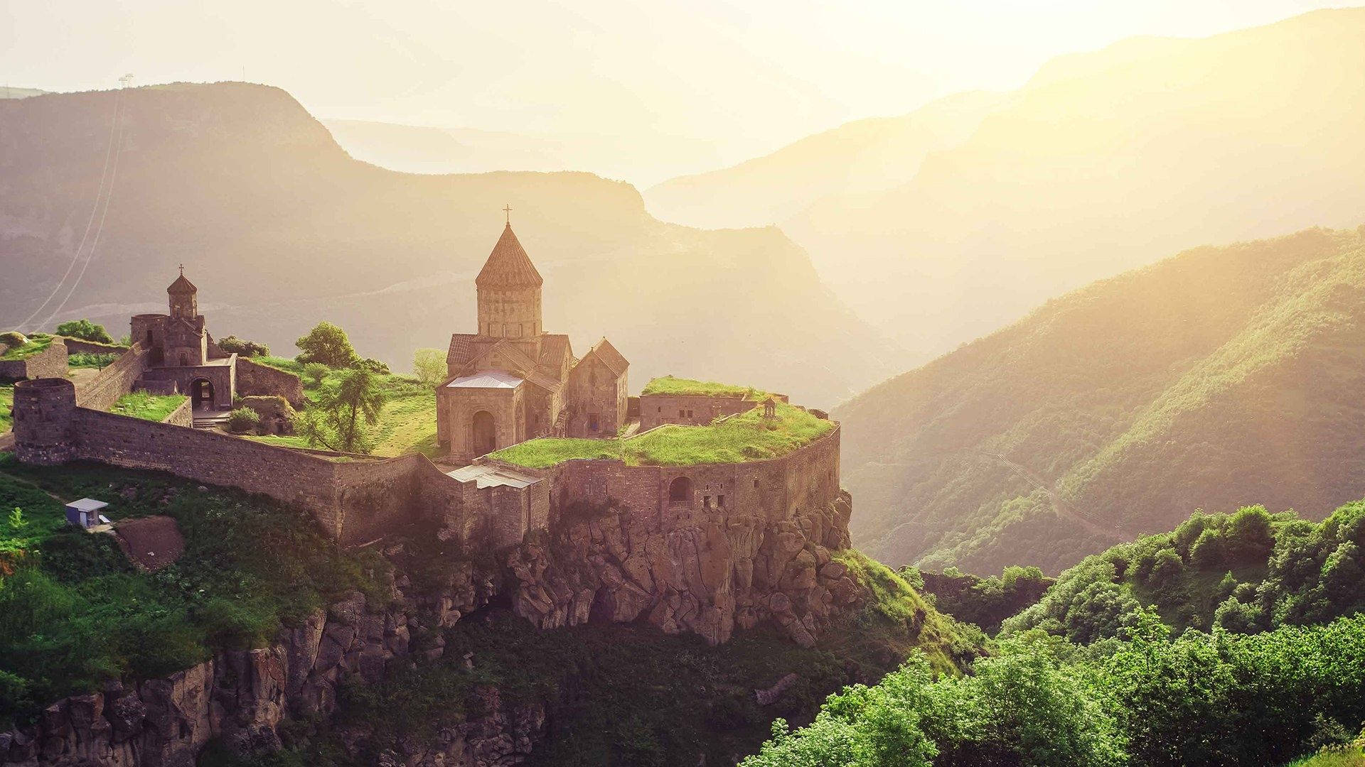 Armenia 桌布 壁紙 — 古老石頭修道院棲息在懸崖邊，俯瞰著沐浴在金色日出光芒中的迷霧綠色山谷。
