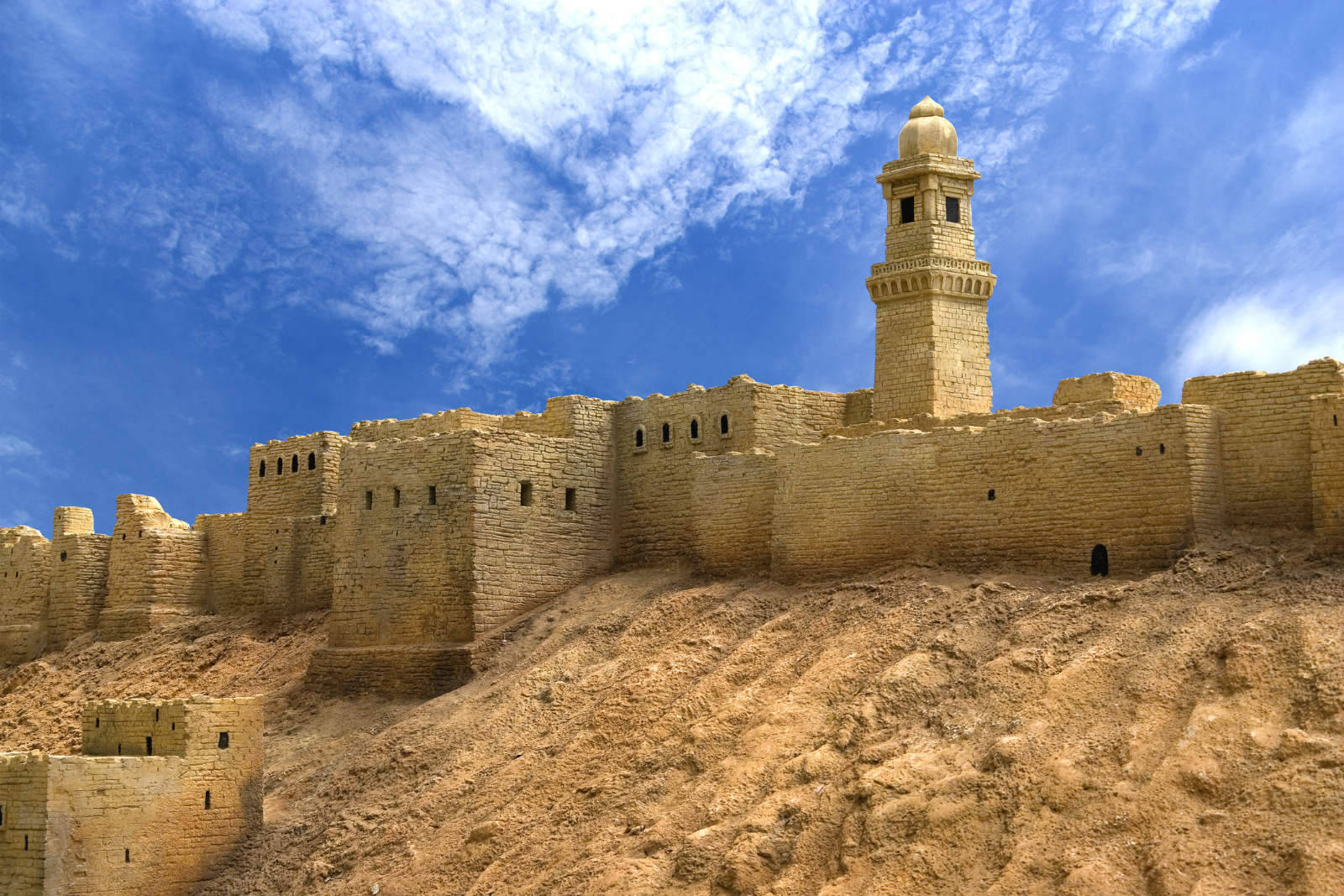Syria 桌布 壁紙 — 古老石頭堡壘，高塔聳立，映襯著蔚藍天空與點點白雲。