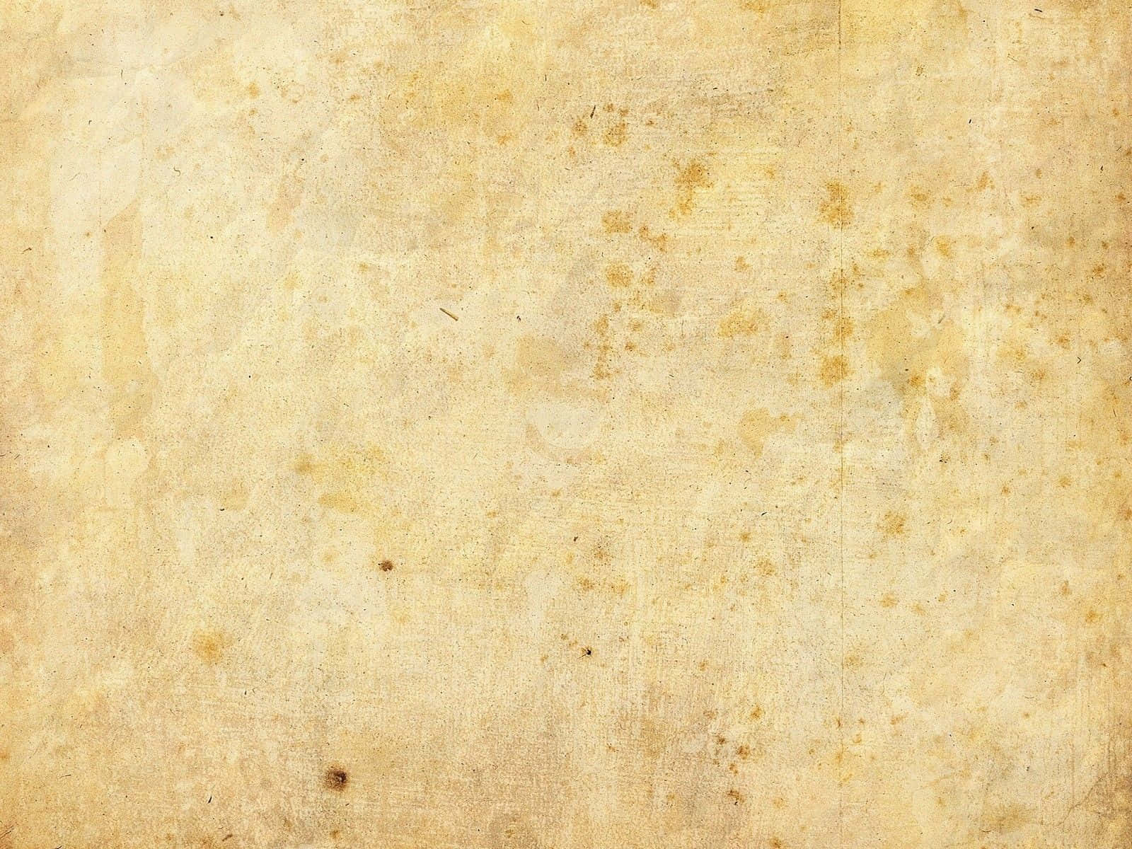 Cream Color 桌布 壁紙 — 古老羊皮紙的特寫，帶有泛黃色調和散佈的污漬，營造出復古紋理表面。