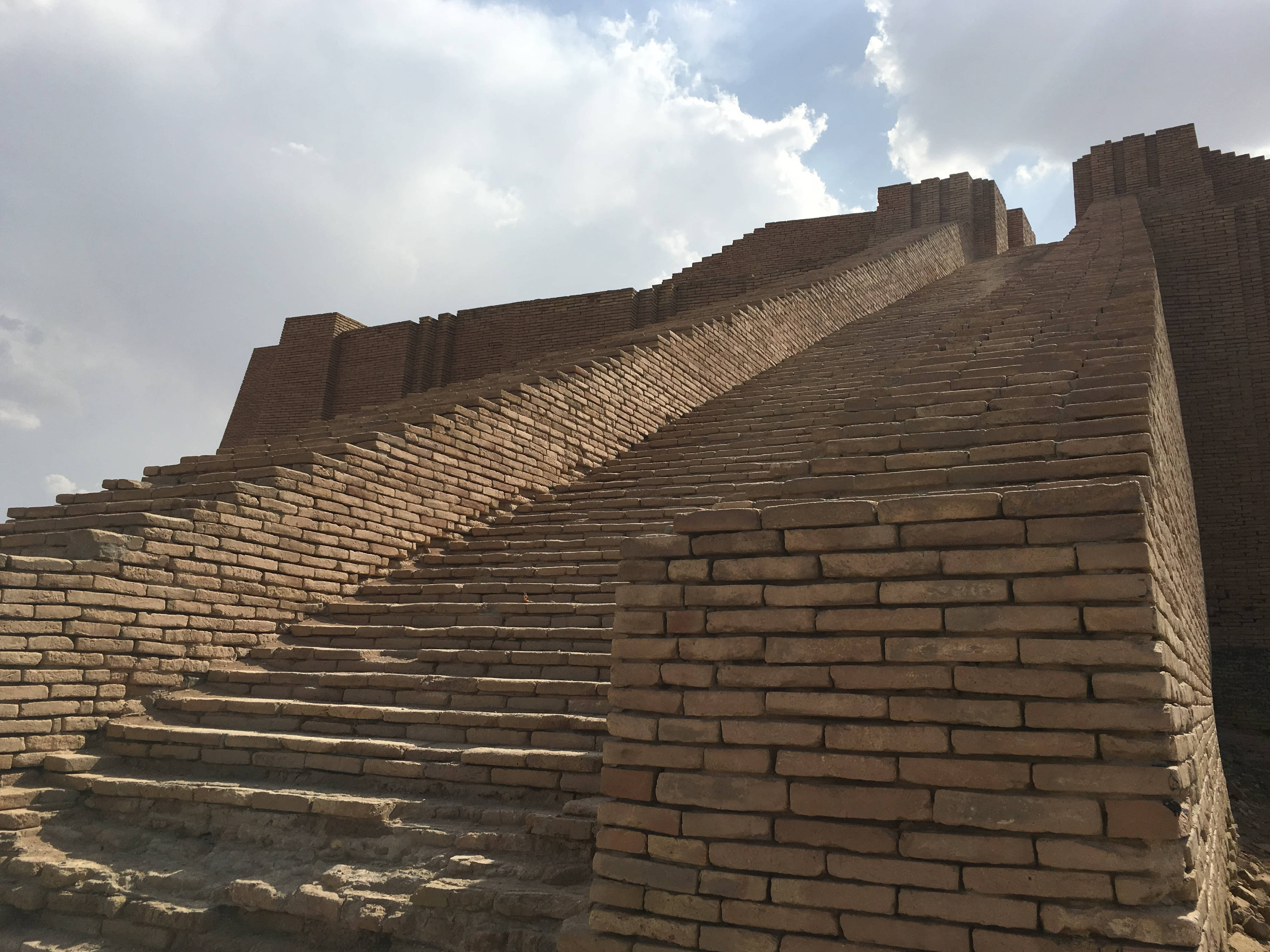 Iraq 桌布 壁紙 — 古老金字形神塔的階梯在局部多雲的天空下升起，展現風化的磚石和宏偉的規模。