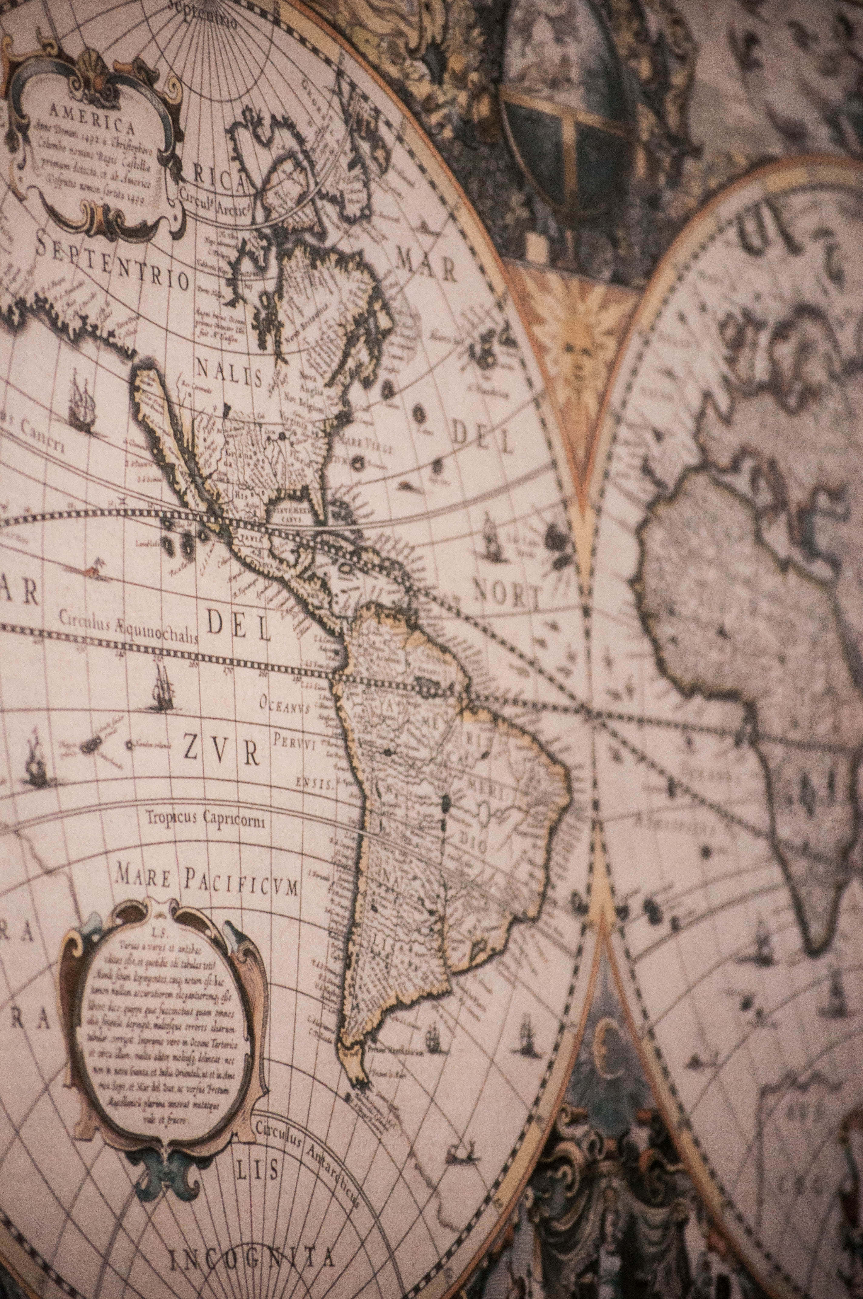 World Map Aesthetic 桌布 壁紙 — 古董世界地圖的特寫，帶有華麗的製圖和褪色的棕褐色調，顯示大陸和裝飾元素。