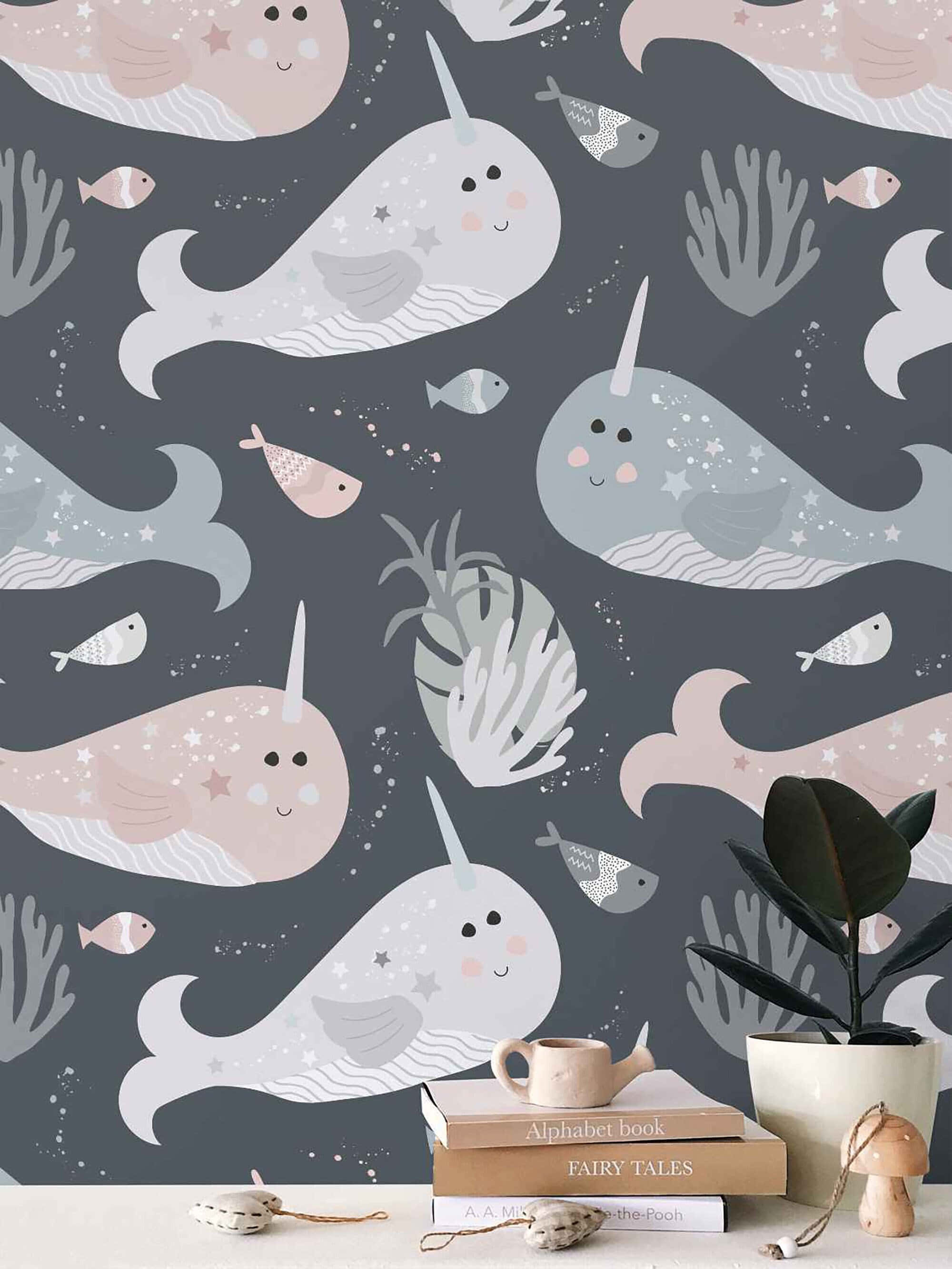 Narwhal 桌布 壁紙 — 可愛的卡通獨角鯨和魚在珊瑚間游動，背景為深灰色，前景有舒適的書本和植物。