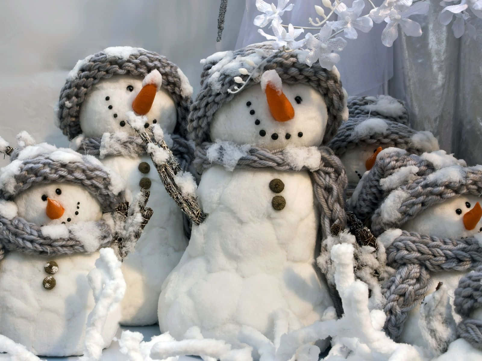 Christmas Snowman 桌布 壁紙 — 可愛的雪人戴著灰色針織帽和圍巾，坐在柔和的冬日陽光下的新雪中。