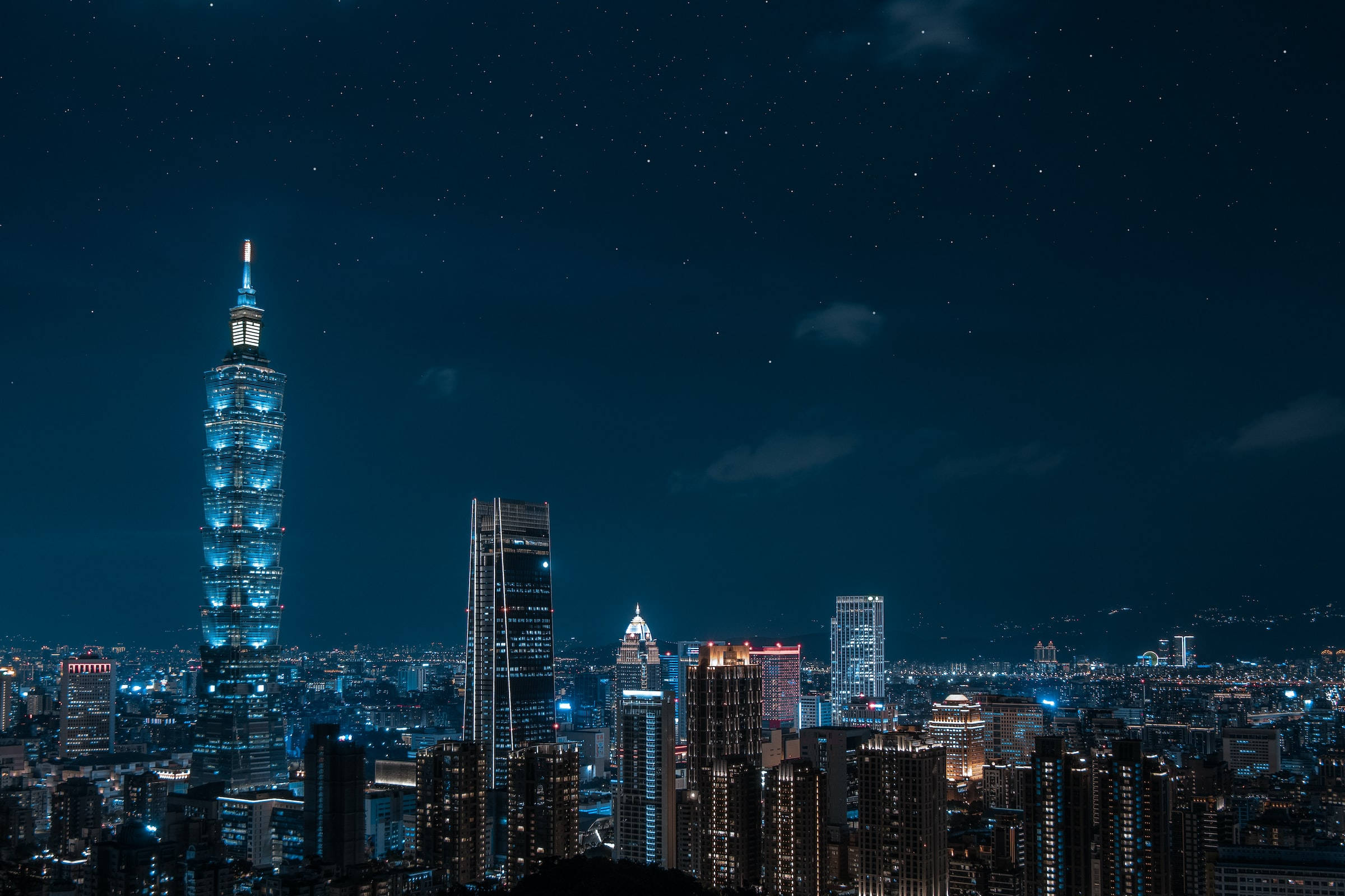 Night Aesthetic 桌布 壁紙 — 台北天際線的迷人夜景，燈火通明的台北101大樓在星空下高聳矗立。