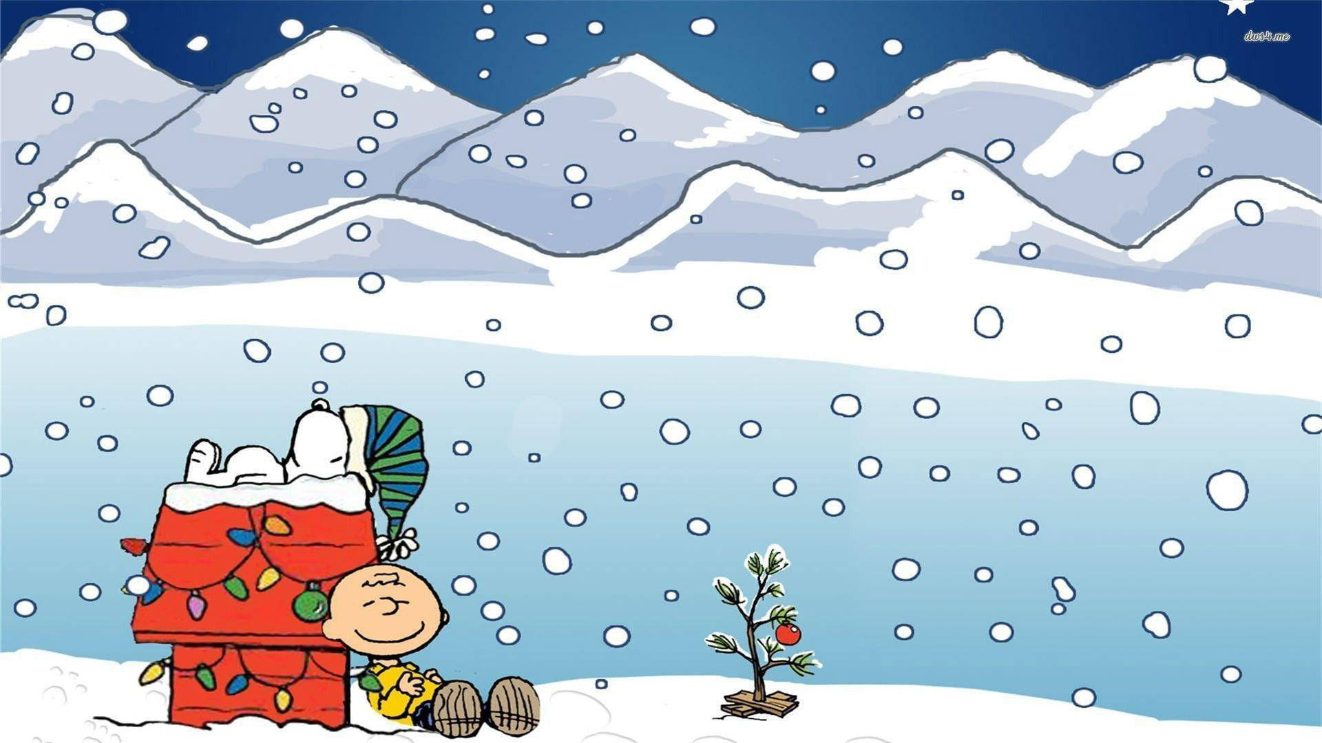 Snoopy Christmas 桌布 壁紙 — 史努比和查理布朗坐在一個裝飾過的紅色狗屋旁邊，背景是白雪皚皚的冬季景觀，飄著雪花，遠處有山脈。