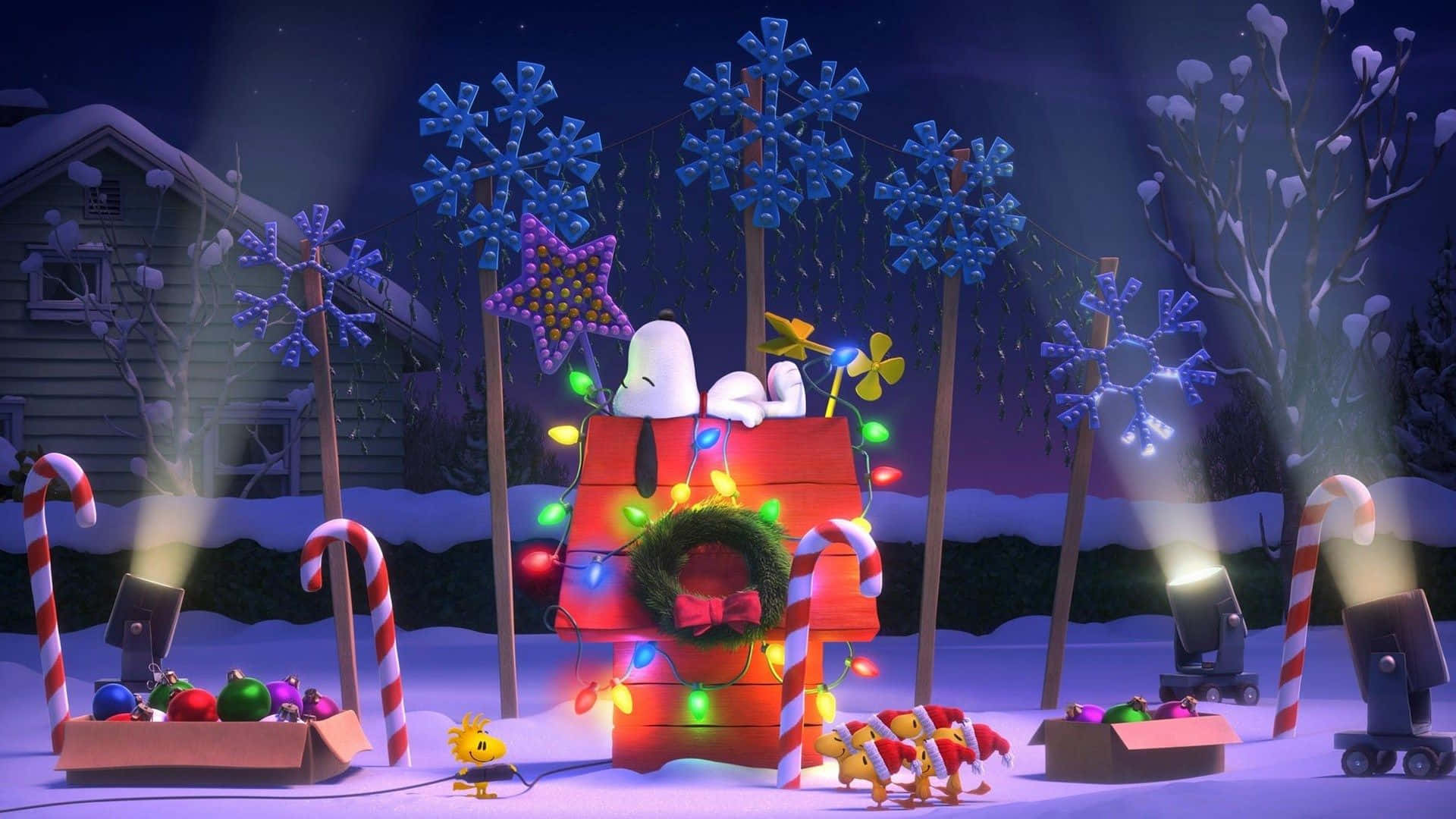 Christmas Movie 桌布 壁紙 — 史努比在他喜慶的紅色狗屋中，狗屋裝飾著燈飾、拐杖糖和雪花，背景是繁星點點的冬夜天空。