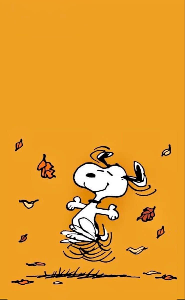 Snoopy Fall 桌布 壁紙 — 史努比在橙色背景上快樂地奔跑穿過飄落的秋葉。