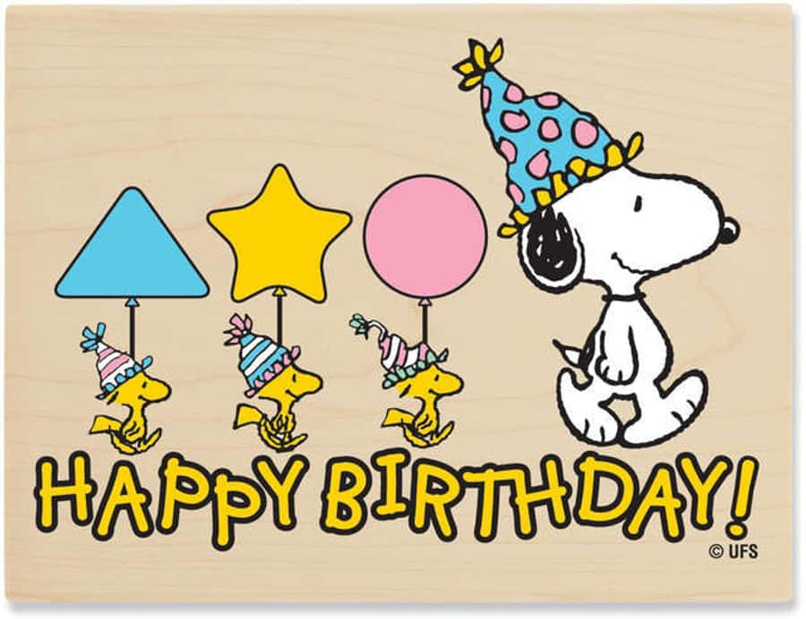 Charlie Brown Birthday 桌布 壁紙 — 史努比戴著波點派對帽，在木質背景上微笑，旁邊有三隻小鴨拿著三角形、星星和圓形狀的氣球。