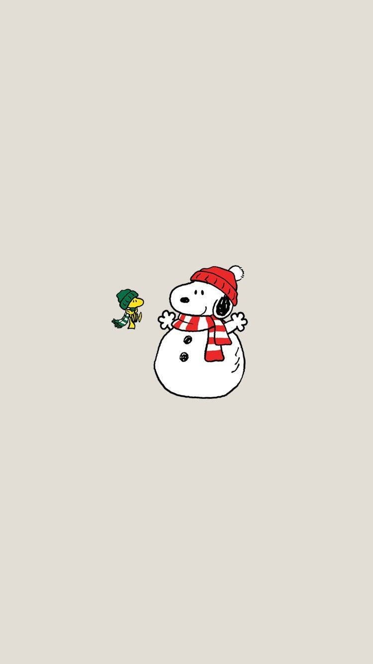 Snoopy Christmas 桌布 壁紙 — 史努比打扮成雪人，戴著紅色帽子和圍巾，站在一隻戴著綠色帽子的小鳥旁邊，背景是米色。