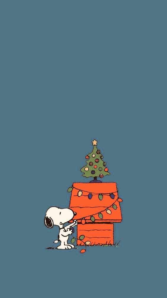 Snoopy Christmas iPhone 桌布 壁紙 — 史努比用燈串和小聖誕樹裝飾他的紅色狗屋，背景為純藍色。