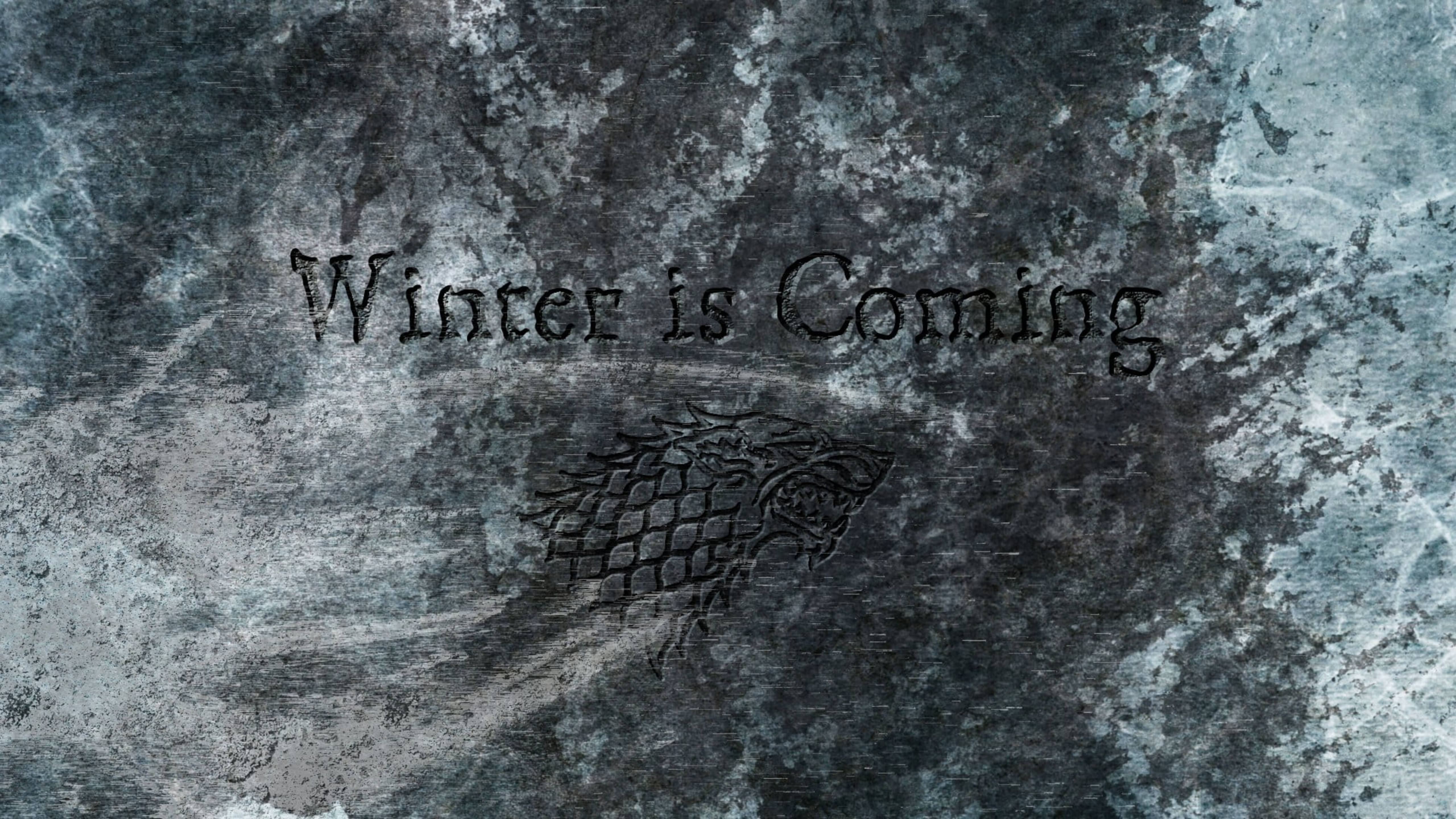 House Stark 桌布 壁紙 — 史塔克家族冰原狼徽章及「Winter is Coming」字句刻在冰藍與灰色質感的冰石上。