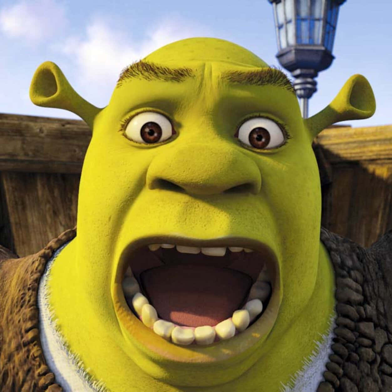 Shrek Funny 桌布 壁紙 — 史瑞克在藍天下瞪大眼睛、張開嘴巴，露出驚訝表情的特寫。