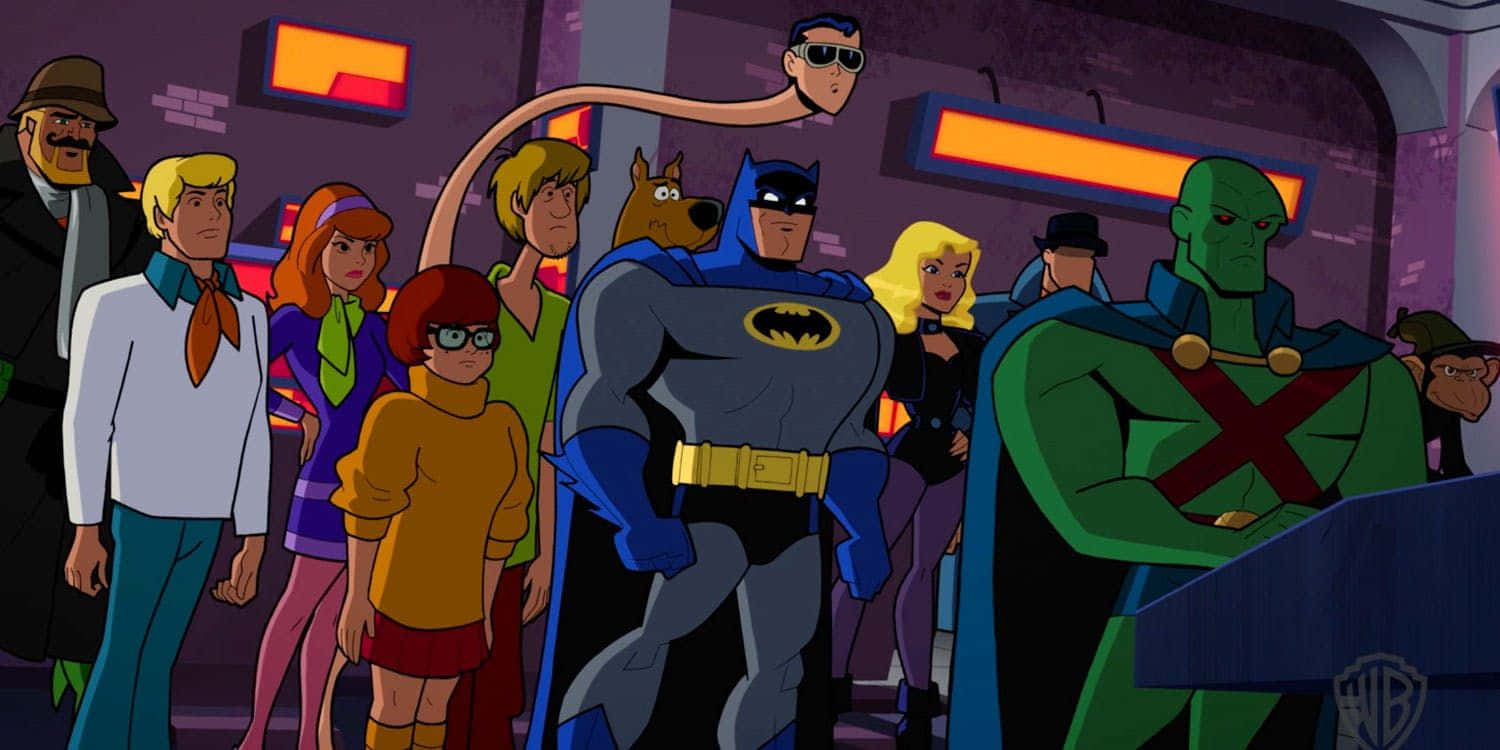 Batman The Brave And The Bold 桌布 壁紙 — 史酷比幫與蝙蝠俠一同站在一個燈光昏暗、帶有發光橙色面板的未來感房間裡。