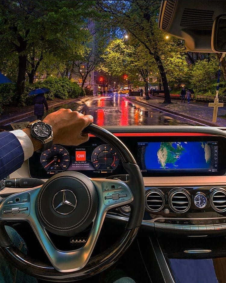 手放在豪華車的方向盤上，在雨夜的城市中行駛。