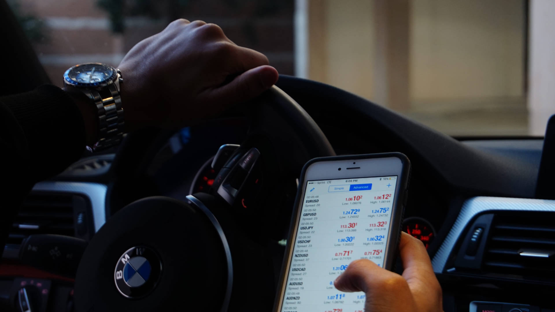 Money 桌布 壁紙 — 司機的手握著BMW方向盤，另一隻手則拿著顯示叫車應用程式及車費估算的電話。