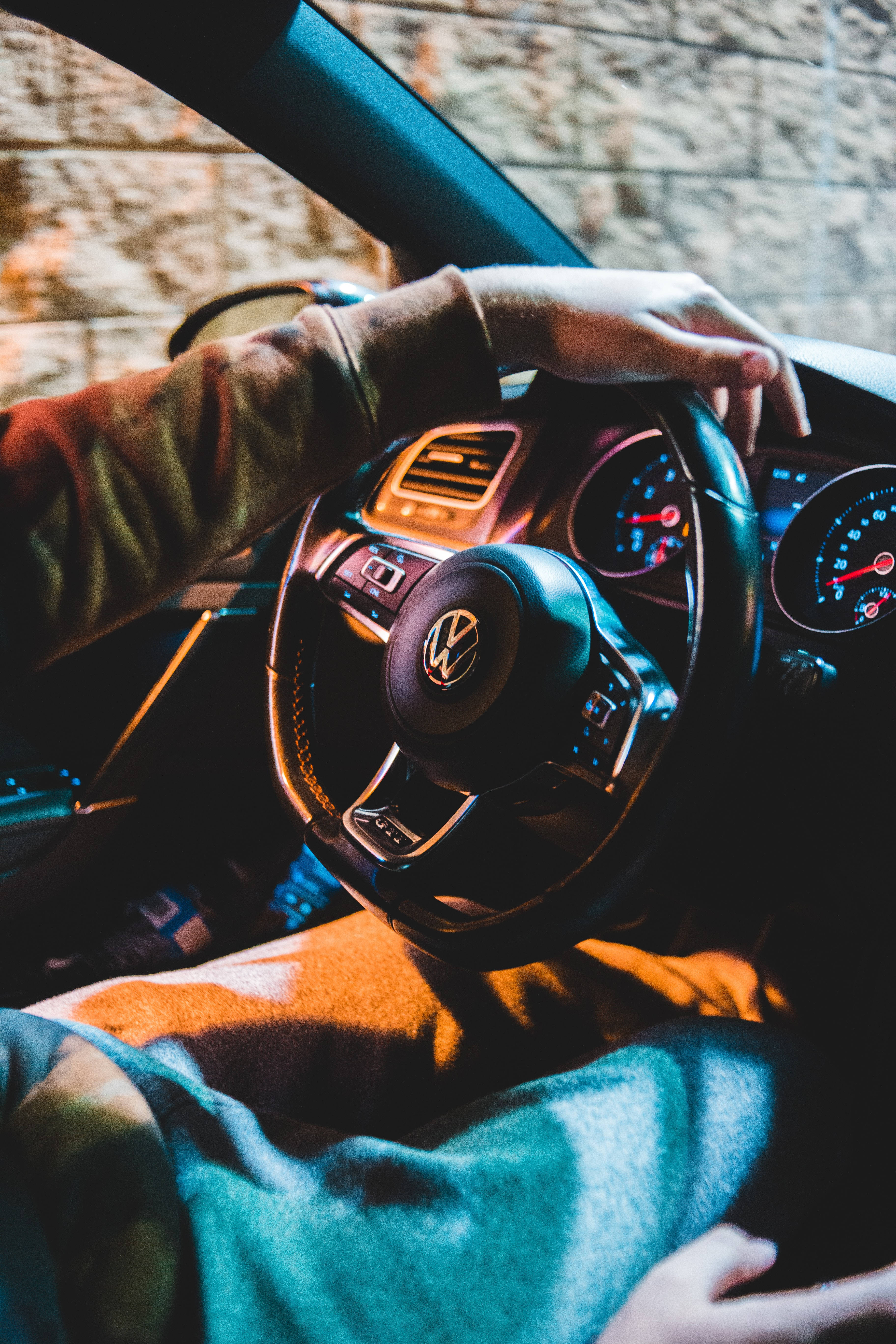 福斯汽車 桌布 壁紙 — 司機的手握著福斯汽車的方向盤，在溫暖的車內燈光下，窗外可見磚牆。