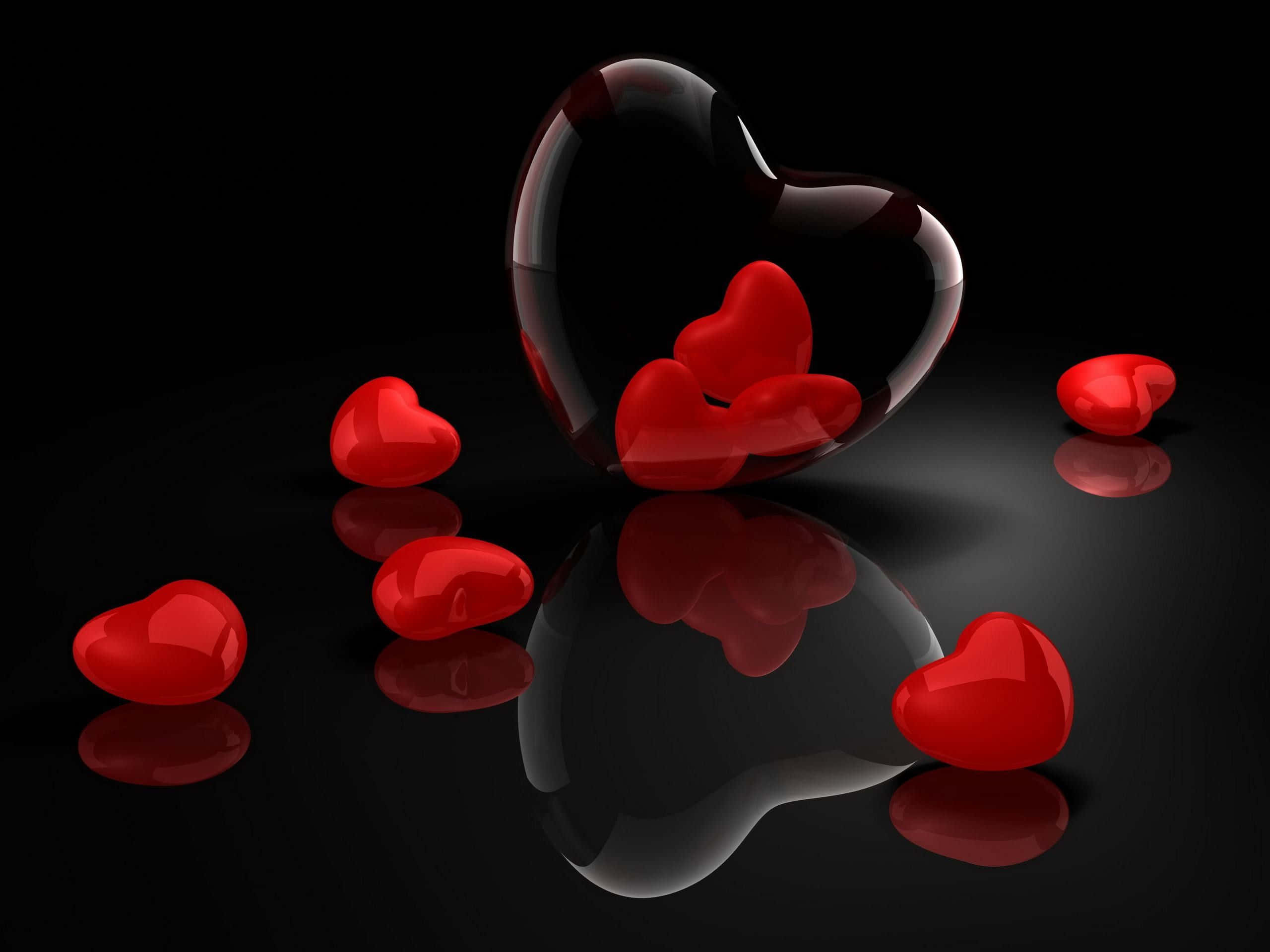 Red Heart 桌布 壁紙 — 各種尺寸的光澤紅色愛心放置在反光的黑色表面上，一個大的透明愛心包含較小的愛心。