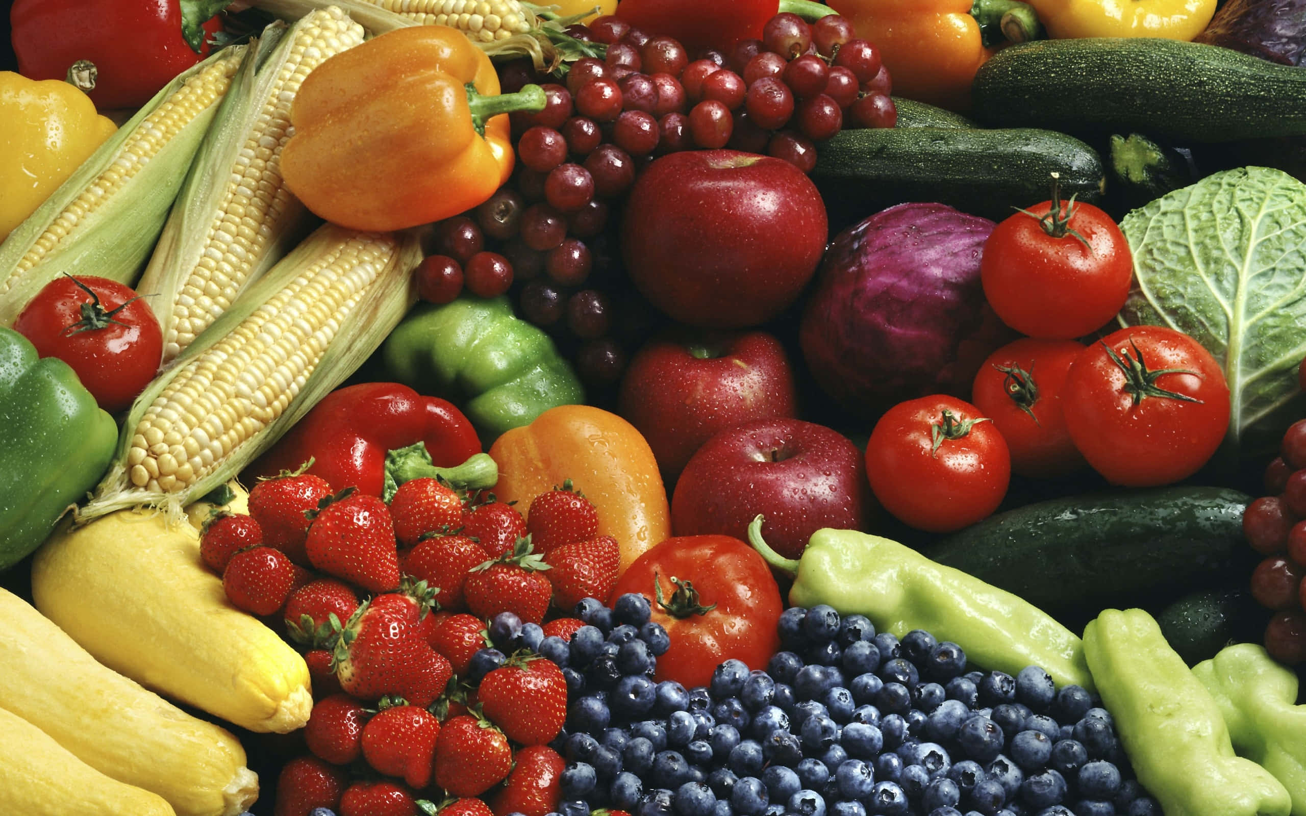 Fruits 桌布 壁紙 — 各種新鮮水果和蔬菜的鮮豔特寫，包括草莓、玉米、葡萄和番茄。