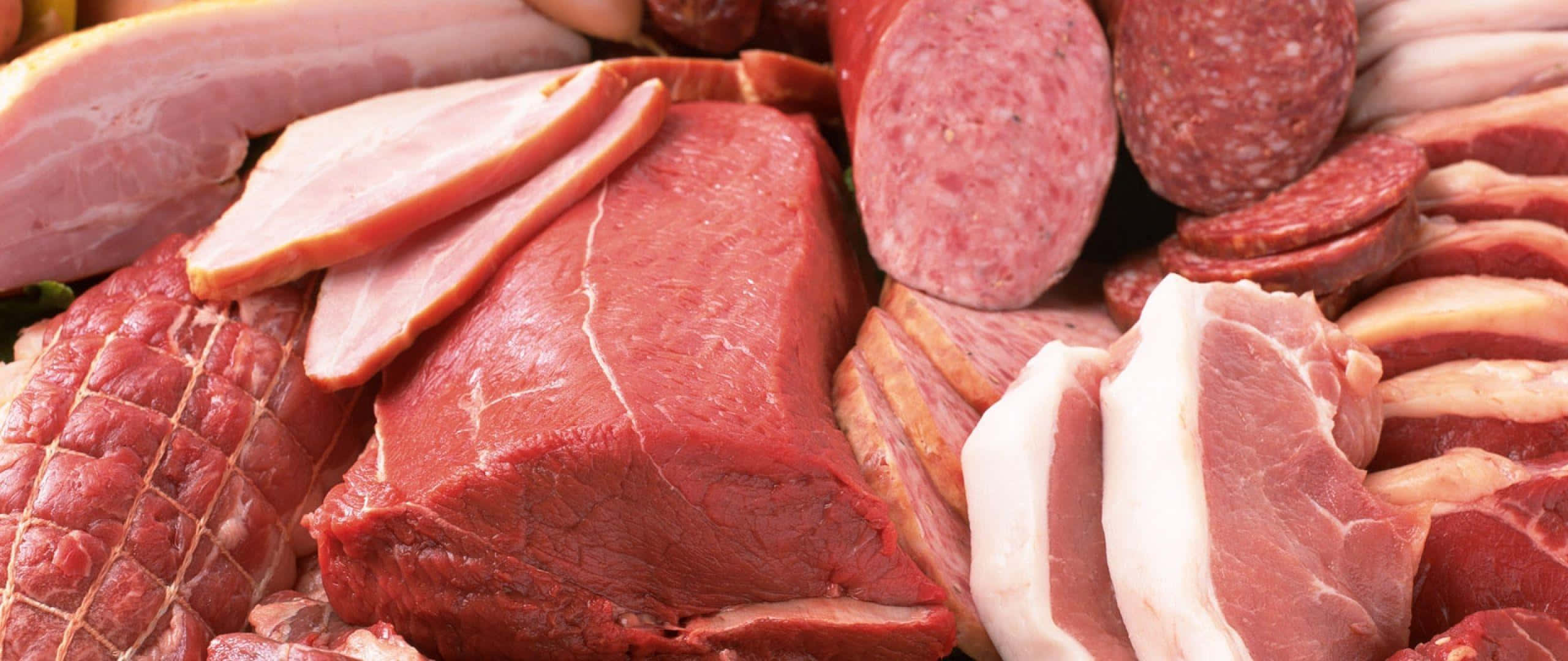 Red Meat 桌布 壁紙 — 各種生肉（包括牛肉、豬肉和香腸）的鮮豔特寫，帶有豐富的紅色和粉紅色。