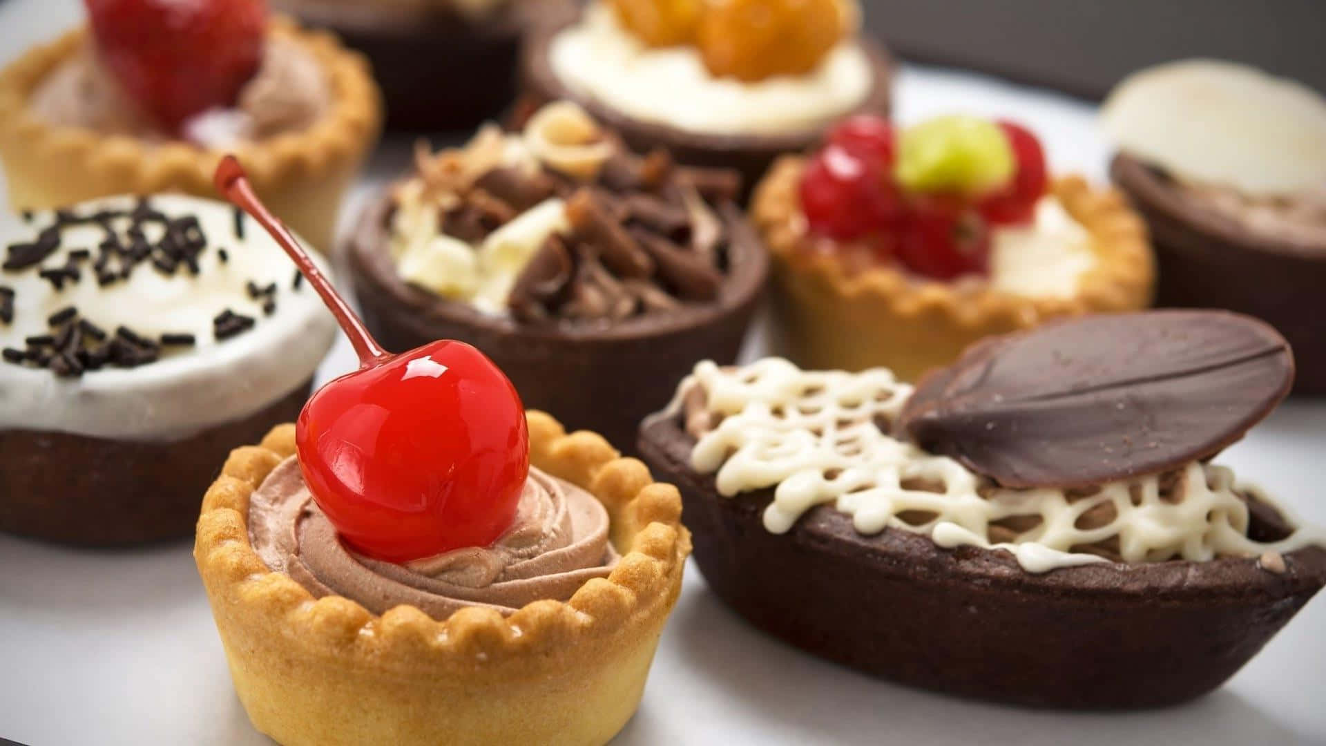 Bakery 桌布 壁紙 — 各種精緻迷你塔的特寫，上面放有櫻桃、巧克力碎和新鮮莓果。