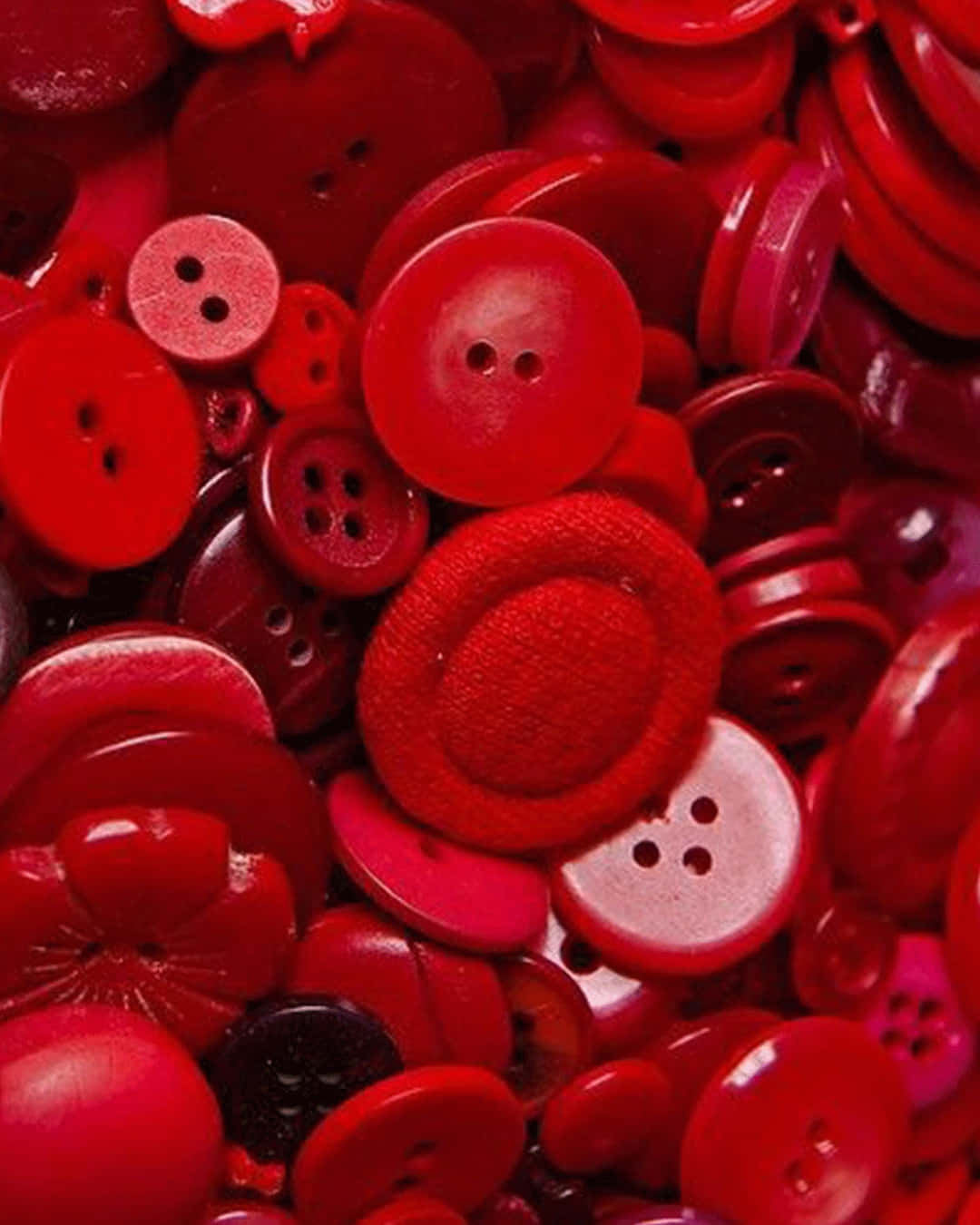 Cute Red 桌布 壁紙 — 各種色調、質地和孔數的紅色鈕扣堆疊在一起的鮮明特寫。