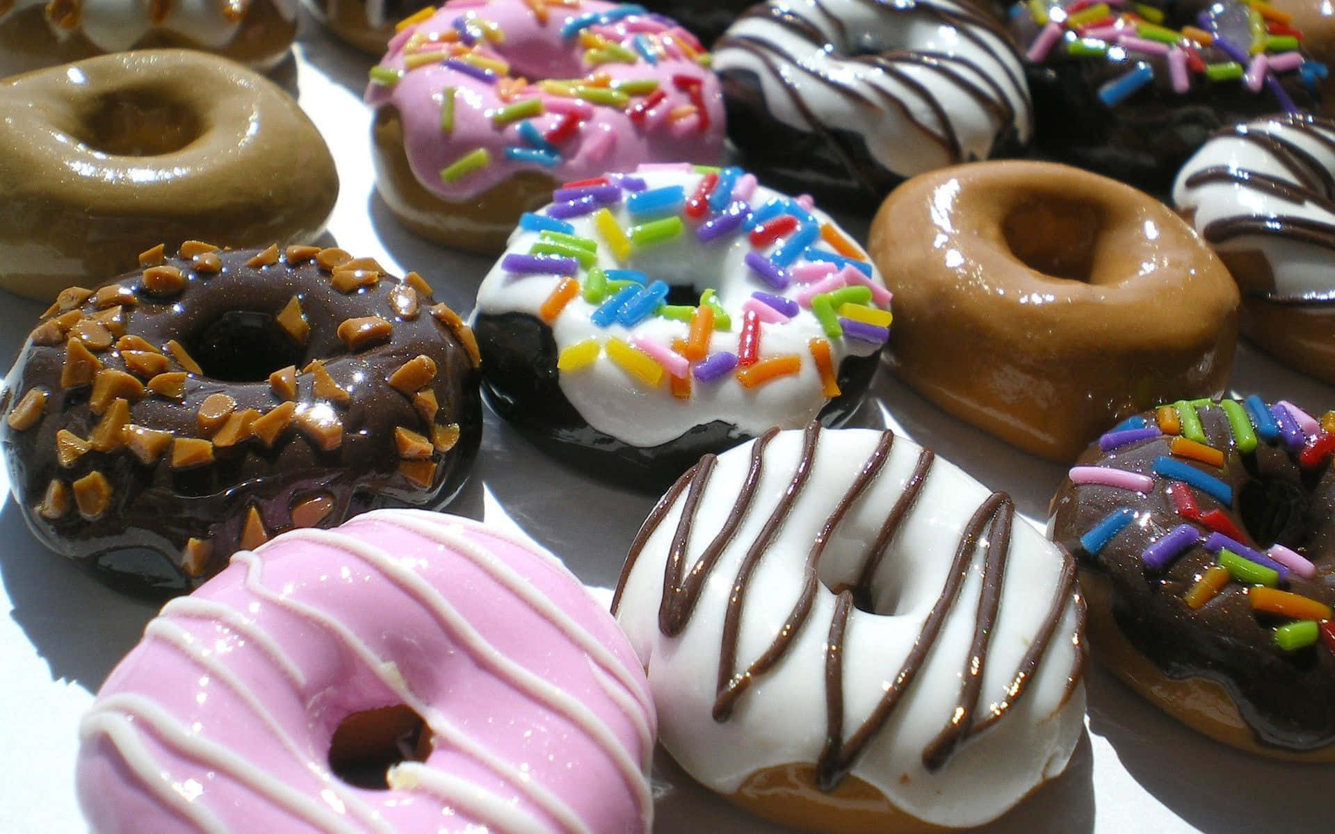 donuts 桌布 壁紙 — 各種釉面裝飾甜甜圈的近距離特寫，上面有彩色糖粒和巧克力淋醬。