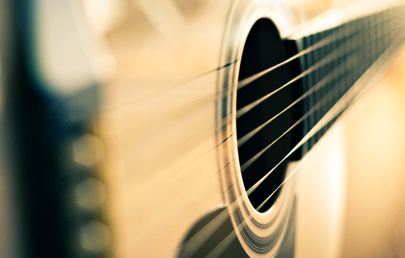 Acoustic Guitar 桌布 壁紙 — 吉他音孔和琴弦的特寫，沐浴在溫暖的金色光線中，背景柔和模糊。