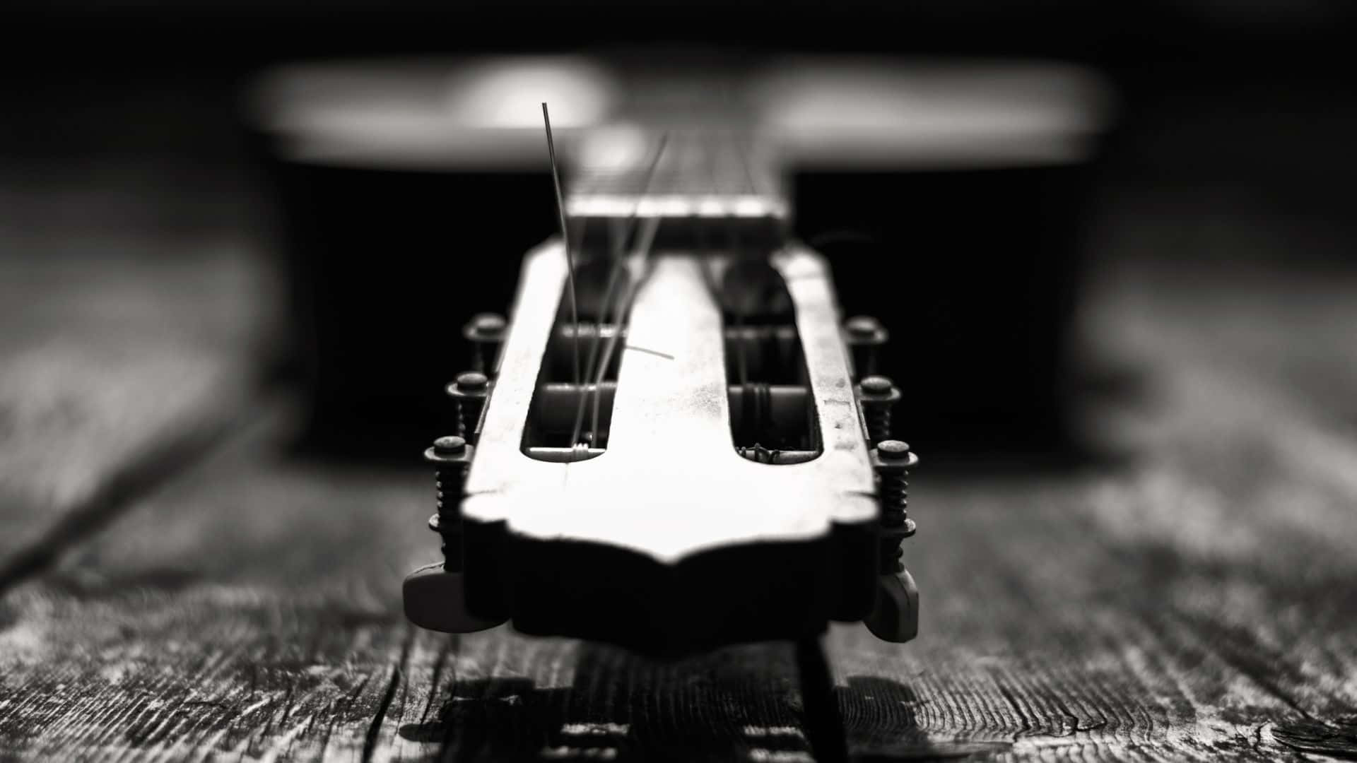 Black And White Guitar 桌布 壁紙 — 吉他頭部特寫黑白照片，放置於經風化的木質表面上，景深較淺。