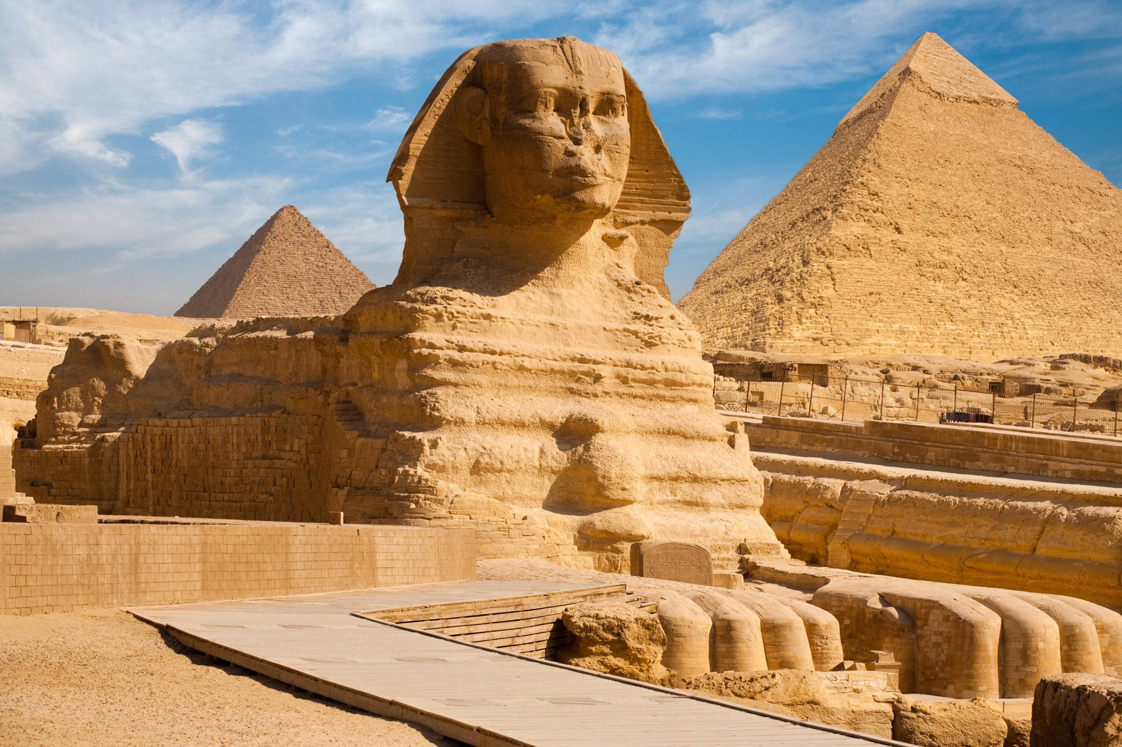 Egypt 桌布 壁紙 — 吉薩大獅身人面像在明亮的藍天下雄偉地矗立，背後沙漠中金字塔聳立。