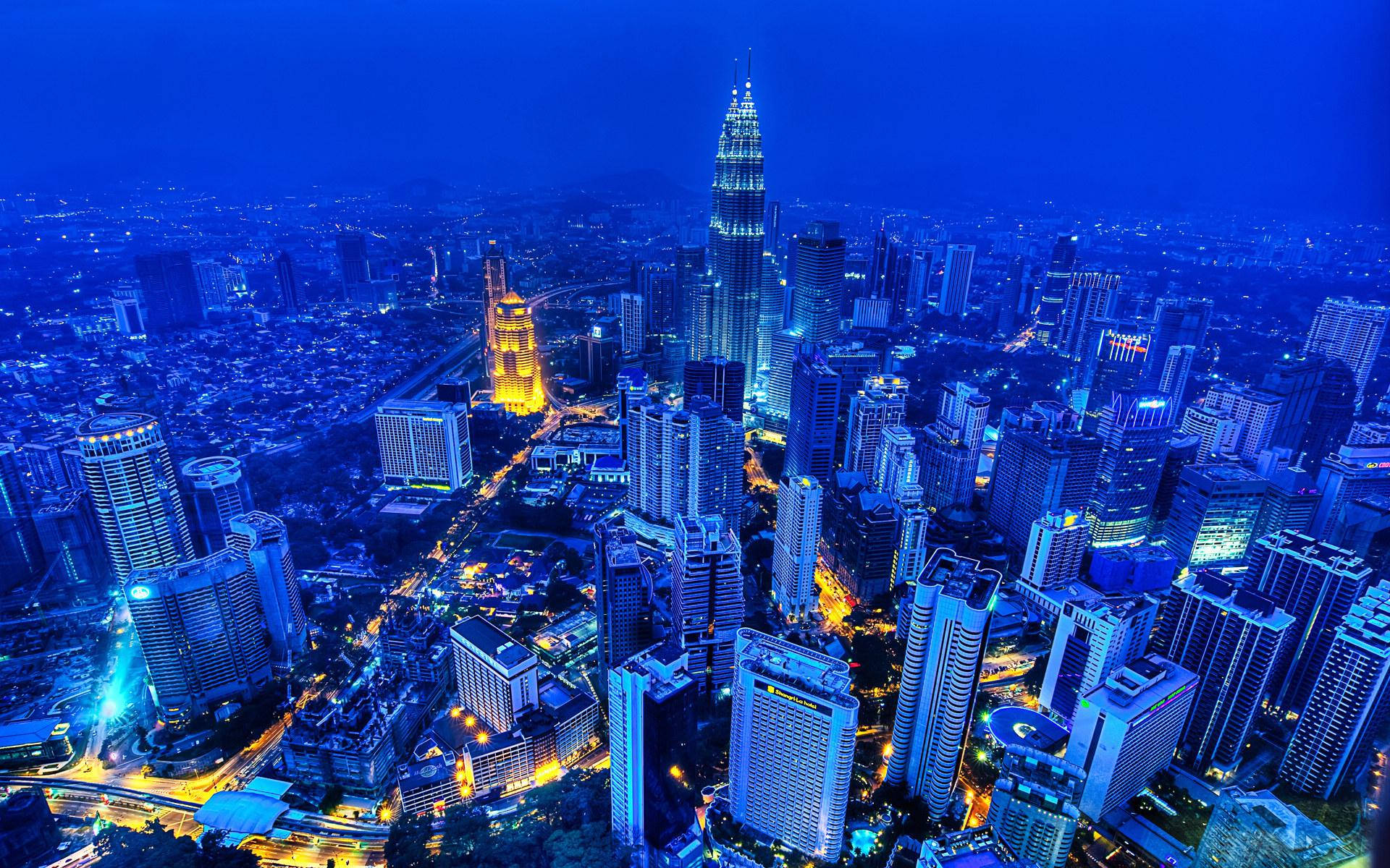 Malaysia 桌布 壁紙 — 吉隆坡天際線的鳥瞰夜景，高聳的摩天大樓在深藍色天空下閃耀。