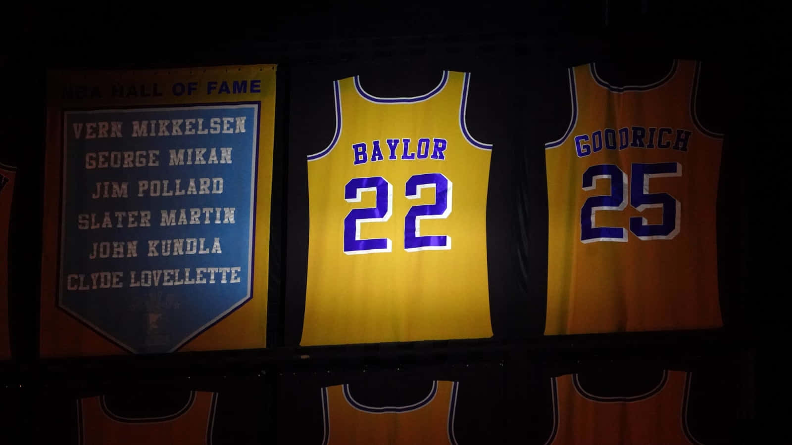 NBA 桌布 壁紙 — 名人堂球衣 Baylor 22 和 Goodrich 25 在黑暗的場館中於聚光燈下懸掛發光。