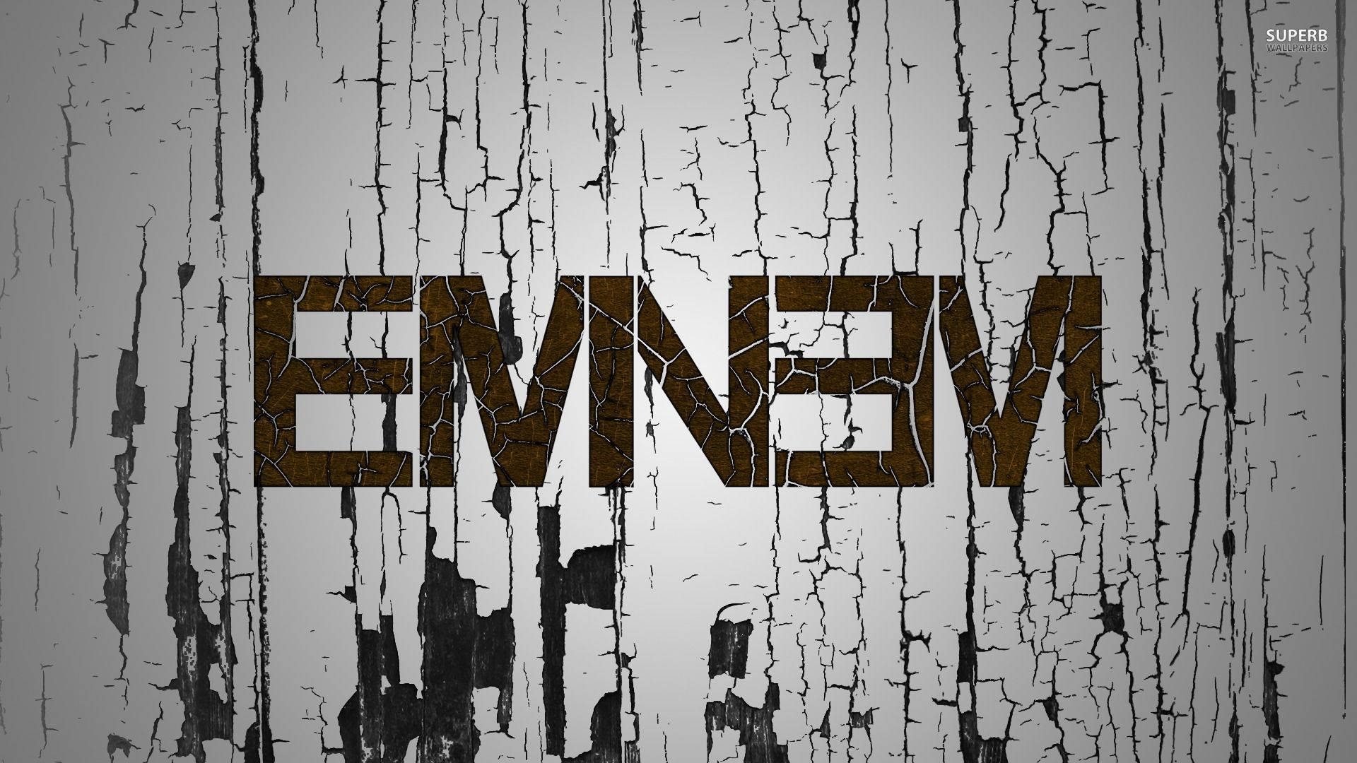 Eminem 桌布 壁紙 — 名字 'EMNEVM' 以裂開的棕色字母在風化的灰色和黑色剝落木紋上突出顯示。
