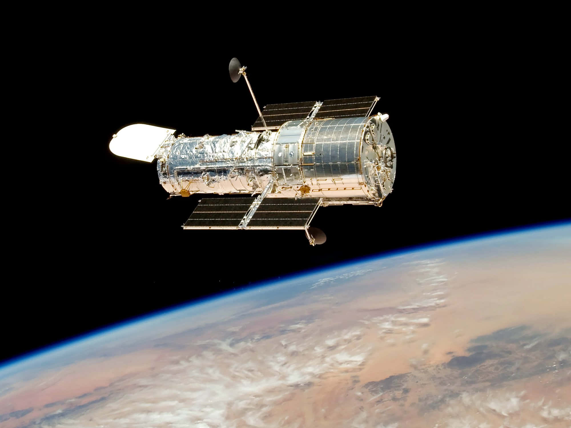 Hubble Space Telescope 桌布 壁紙 — 哈伯太空望遠鏡在太空的漆黑背景下，滑過地球彎曲的地平線。