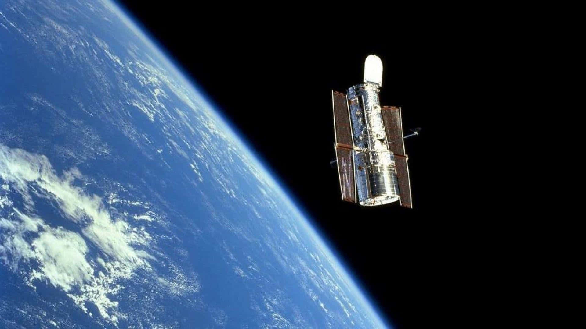 Hubble Space Telescope 桌布 壁紙 — 哈伯太空望遠鏡在漆黑的太空中繞地球運行，藍色行星在下方彎曲。