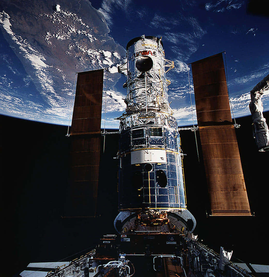 Hubble Space Telescope 桌布 壁紙 — 哈伯太空望遠鏡在軌道上漂浮，地球的藍白雲層在下方彎曲，襯托著太空的漆黑。