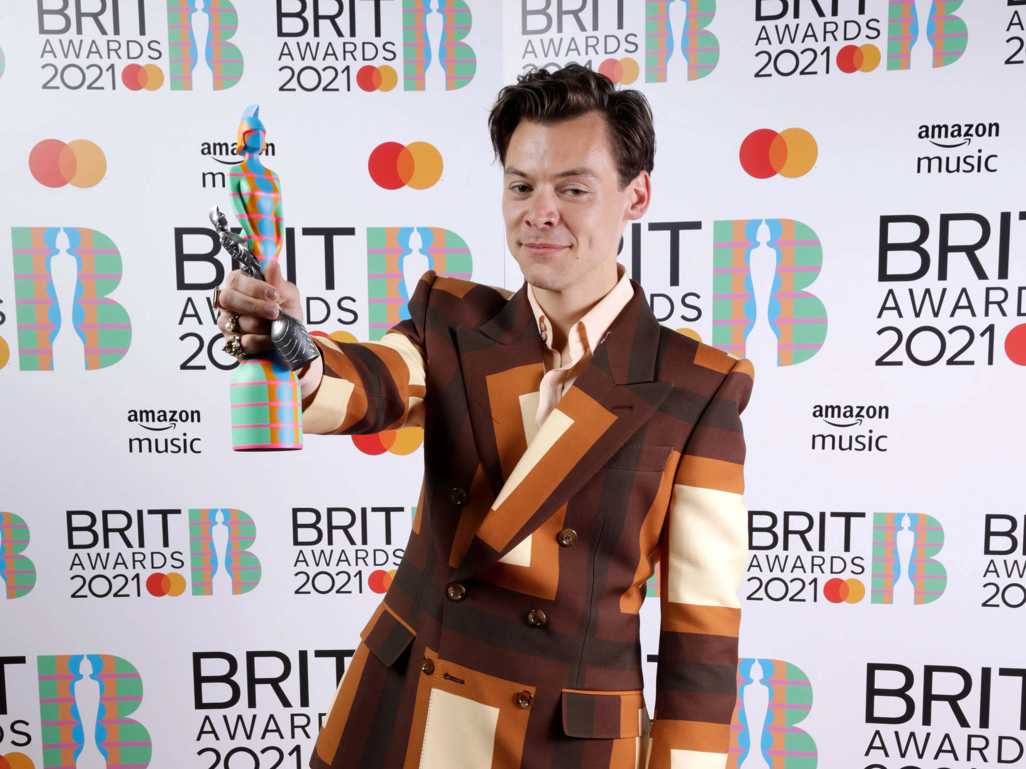 Harry Styles 2021 桌布 壁紙 — 哈利·斯泰爾斯在2021年全英音樂獎紅毯上，穿著大膽的幾何圖案西裝，微笑著手持色彩繽紛的獎項。
