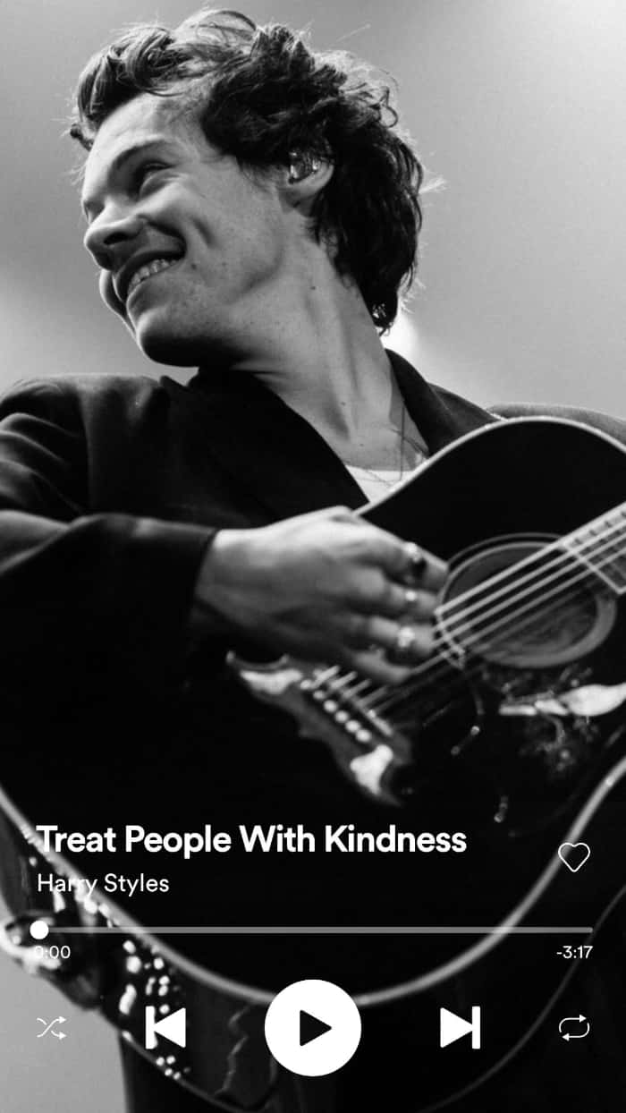 Harry Styles Black And White 桌布 壁紙 — 哈利·斯泰爾斯在一張黑白演唱會照片中微笑著彈奏木吉他。