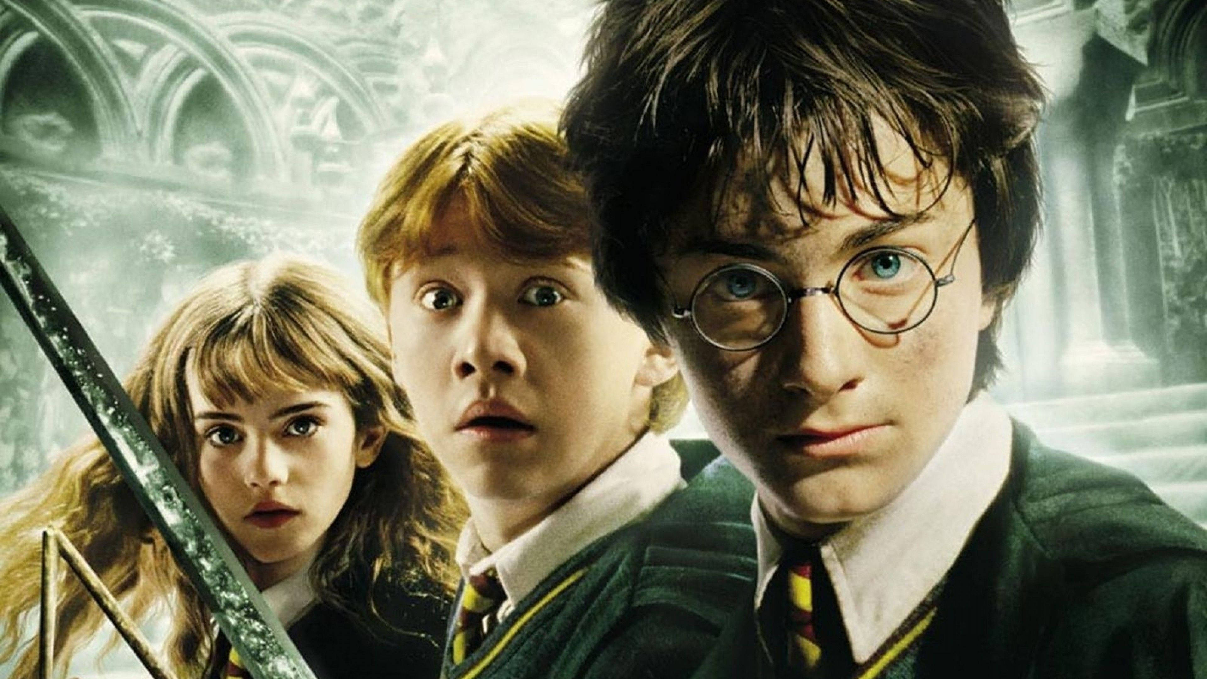 Hermione Granger 桌布 壁紙 — 哈利波特、榮恩和妙麗穿著霍格華茲制服，在哥德式石拱門背景下顯得震驚。
