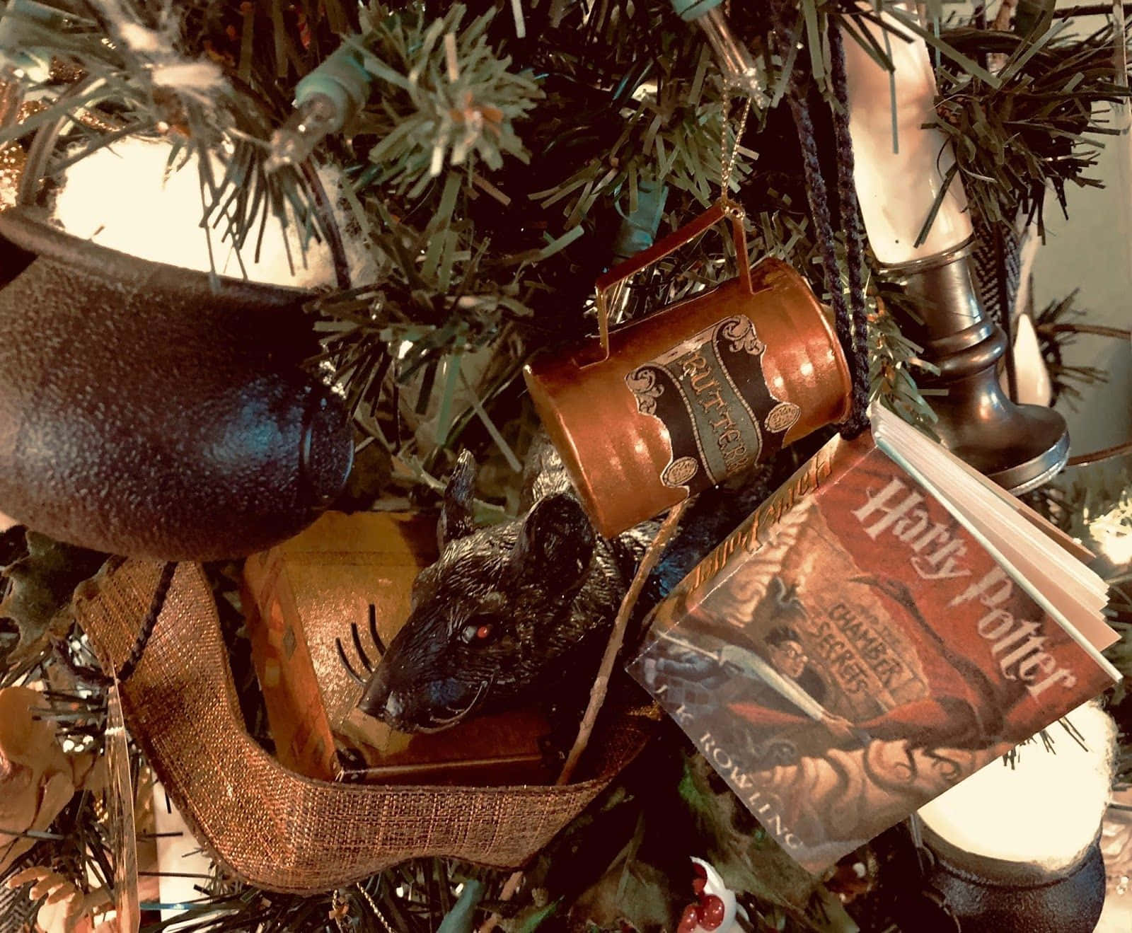 Harry Potter Christmas 桌布 壁紙 — 哈利波特主題聖誕樹的特寫，裝飾著大鍋老鼠書和魔藥瓶飾品。