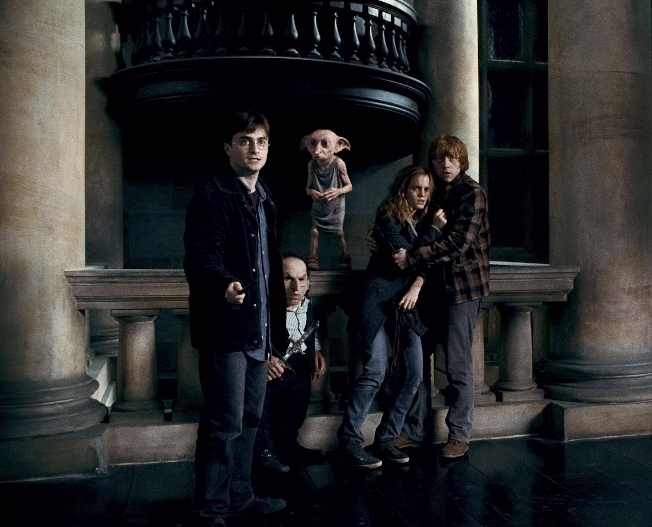 Hermione Granger 桌布 壁紙 — 哈利波特和朋友們緊張地站在一個宏偉的石廳中，家庭小精靈多比懸浮在他們上方。