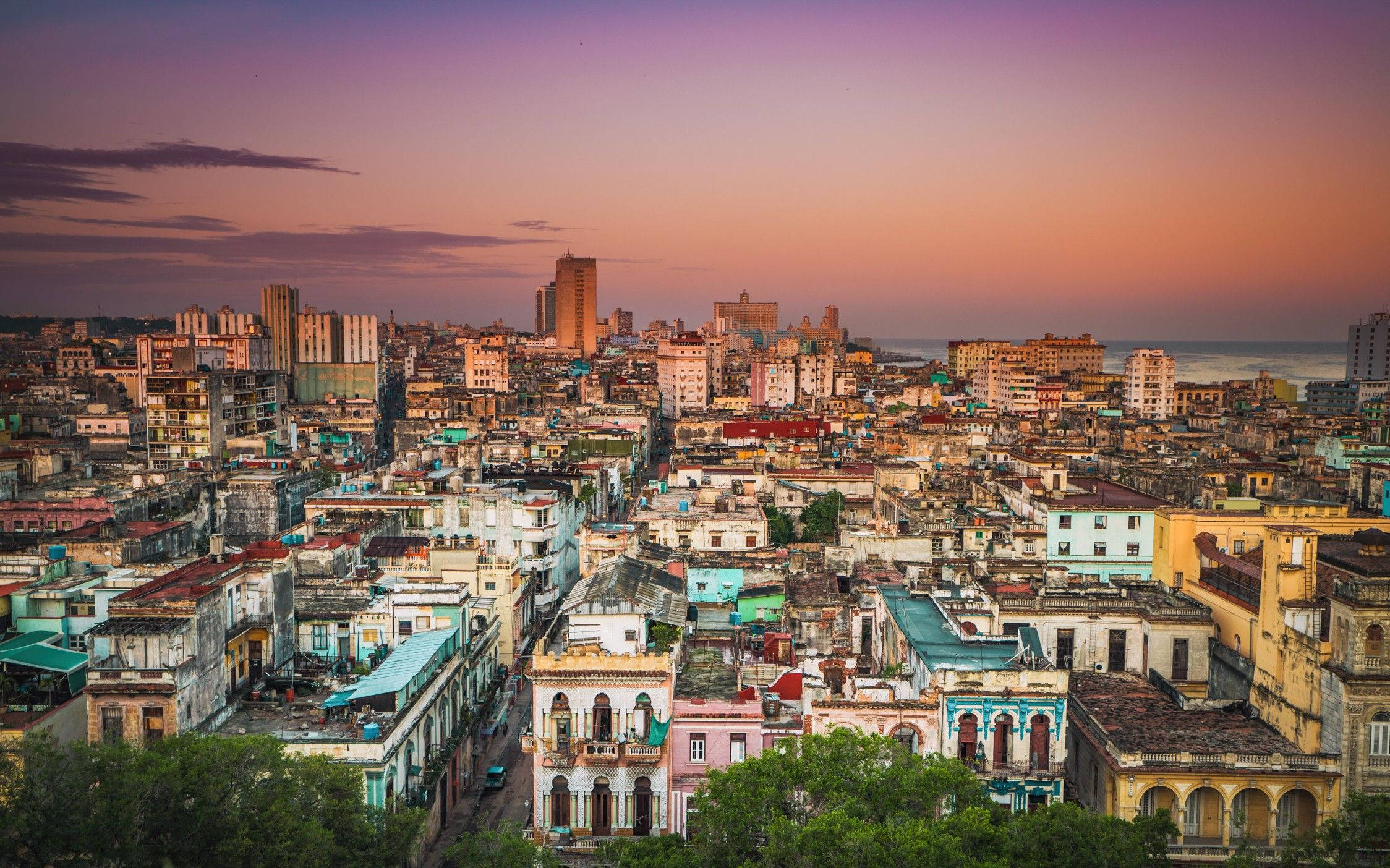 Cuba 桌布 壁紙 — 哈瓦那古巴日落時分的鳥瞰圖，紫橙色天空下，粉彩色的殖民時期建築與現代摩天大樓交相輝映。