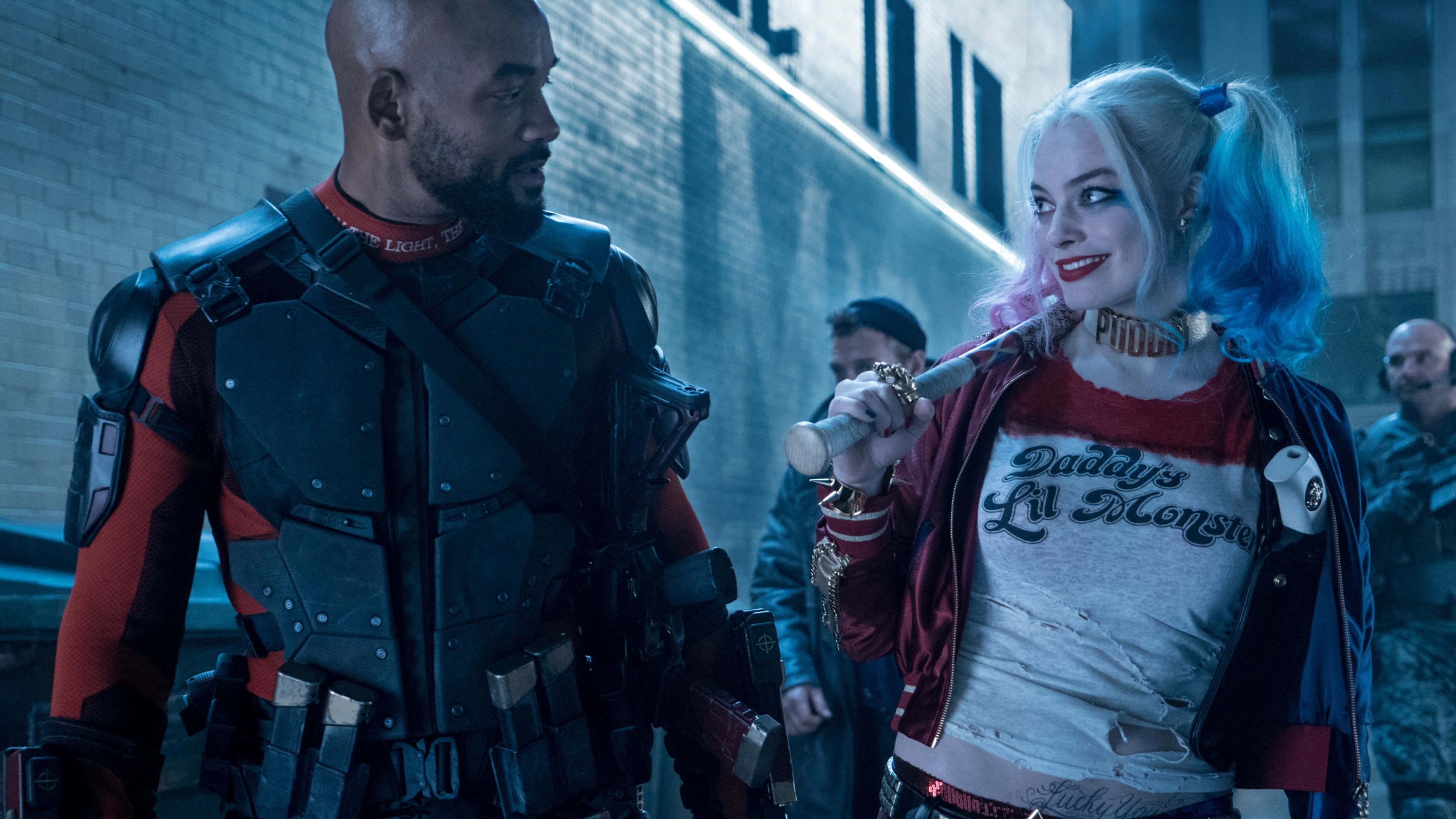 Margot Robbie Harley Quinn 桌布 壁紙 — 哈莉·奎茵（Harley Quinn）擁有藍色和粉紅色頭髮，手持棒球棍，面對一個身穿戰術裝備的光頭男子，背景是磚牆。